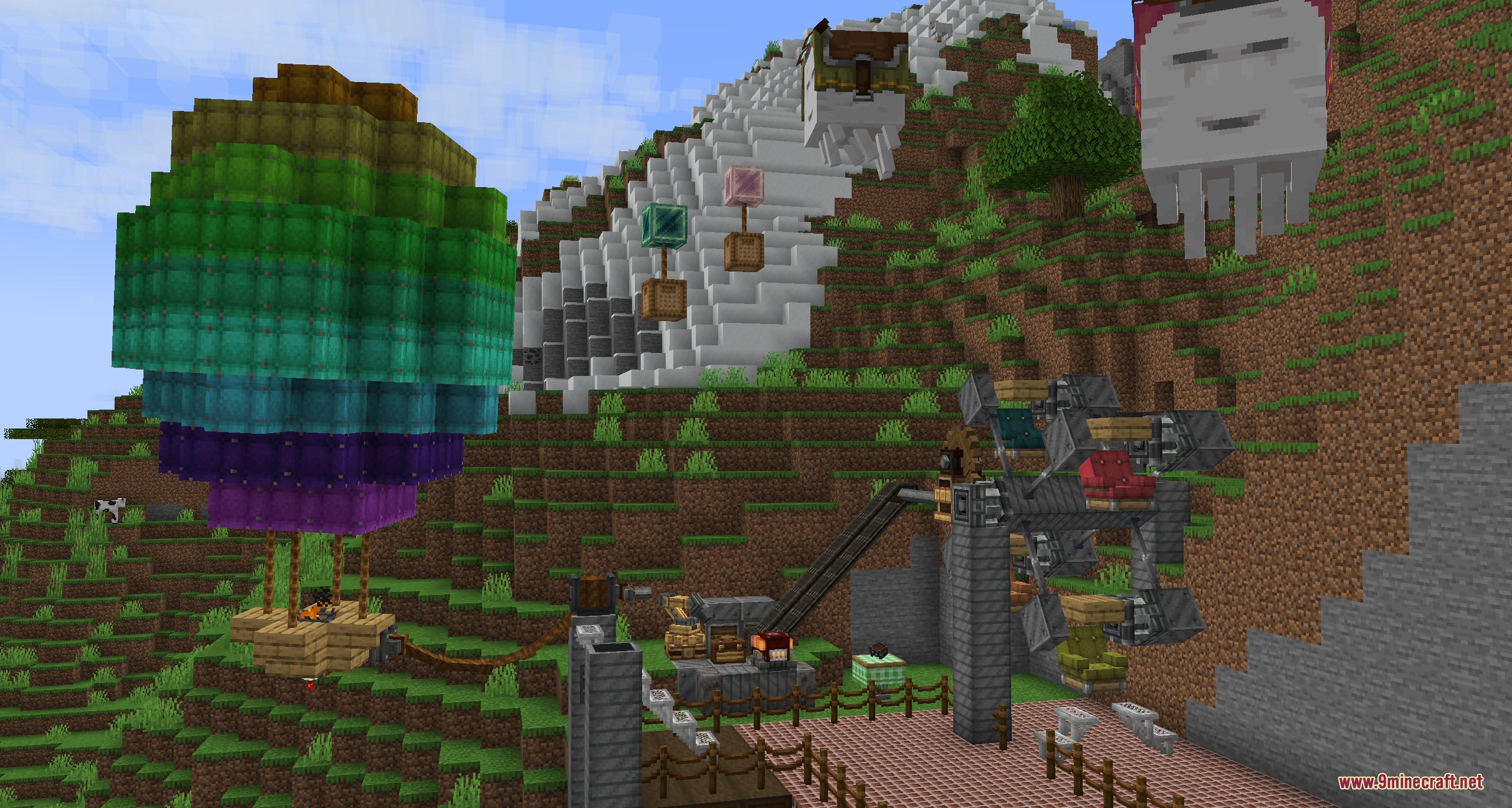 A colorful hot air balloon and mechanical Ferris wheel in a hilly landscape
