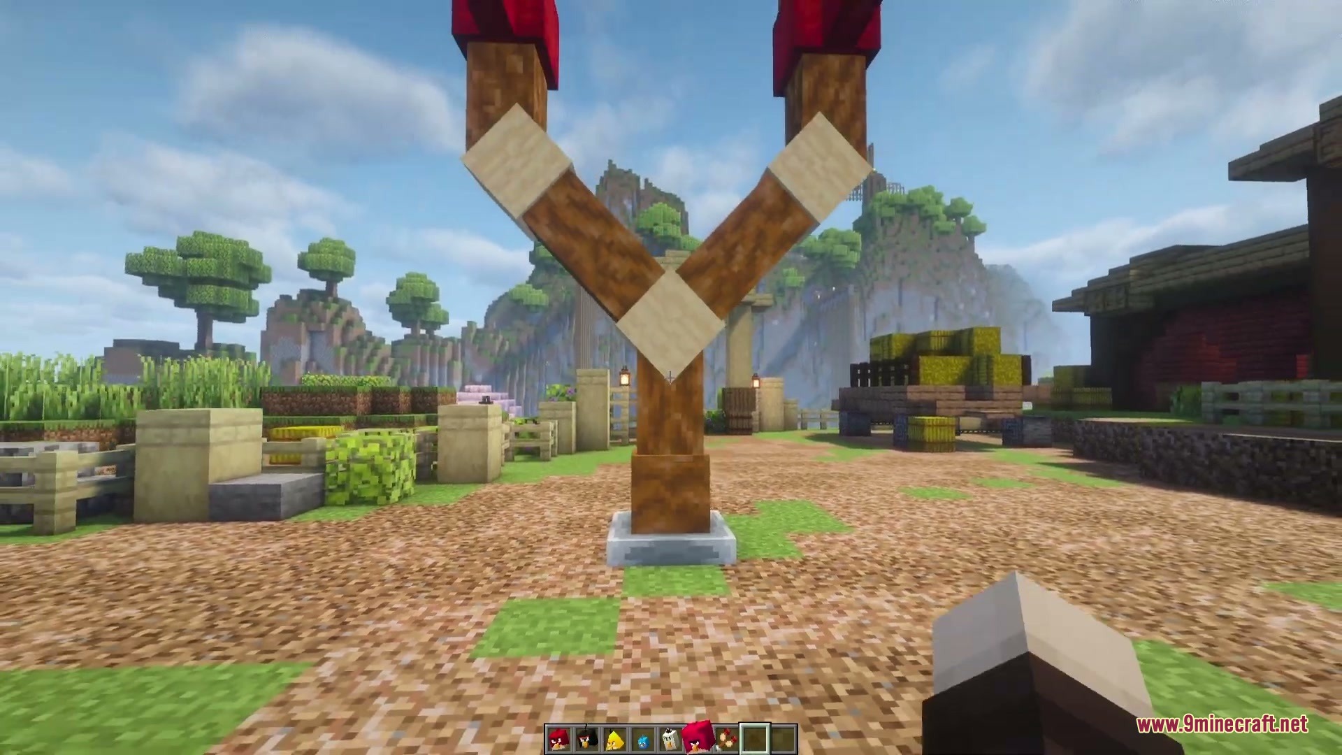 A large wooden slingshot built on a stone base in a village