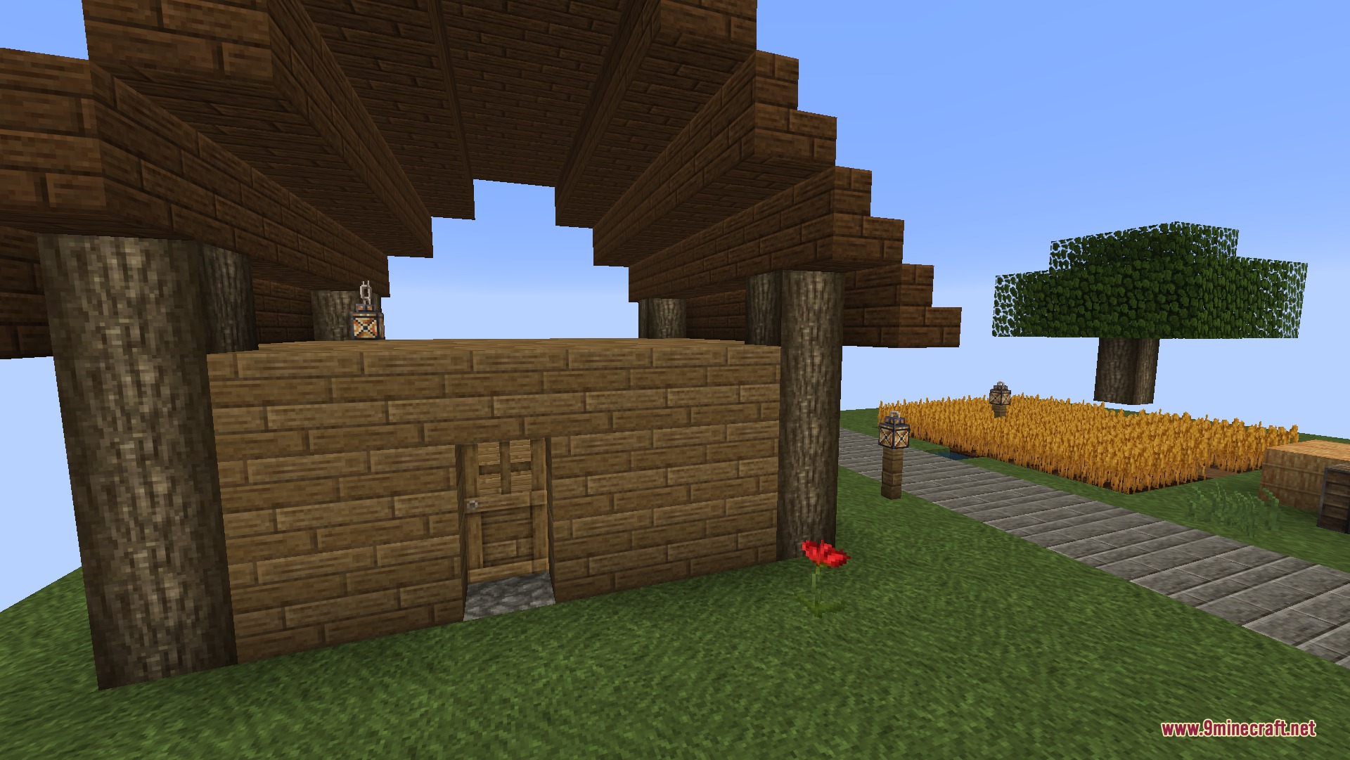A simple wooden house with log pillars and a red flower out front