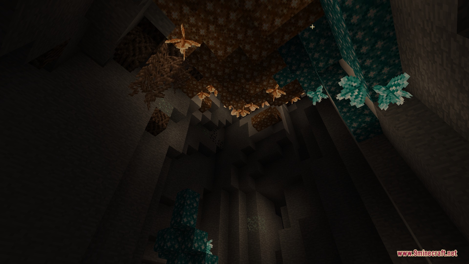 Glowing blue and orange crystals hanging from the ceiling of a dark cave