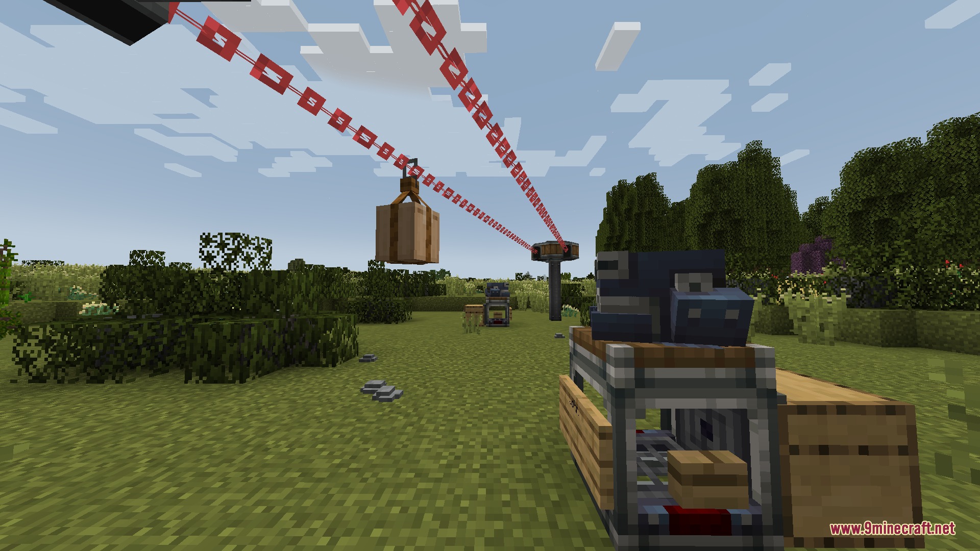 Create Chain Conveyors Compat Mod Screenshot 2 A wooden crate hanging from a red chain conveyor in a field