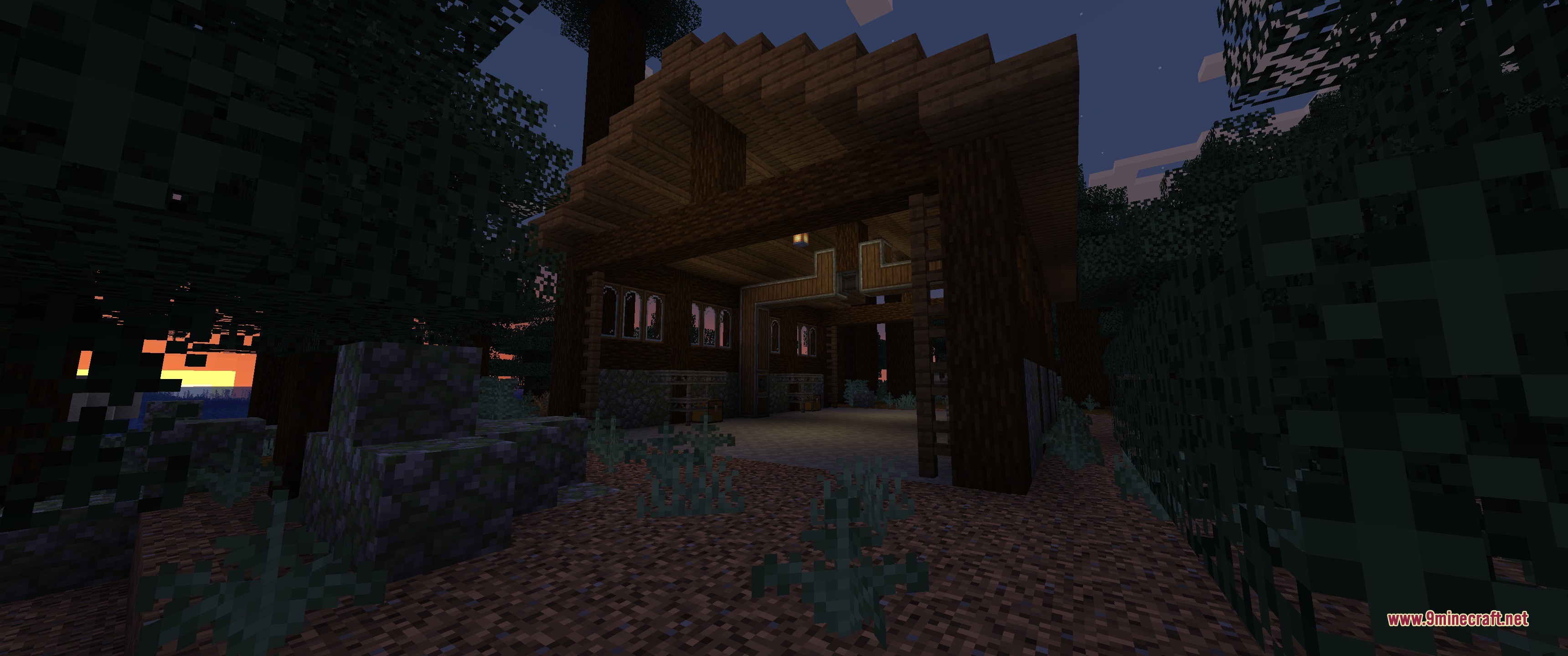 A large wooden hangar structure stands in a dark forest at sunset