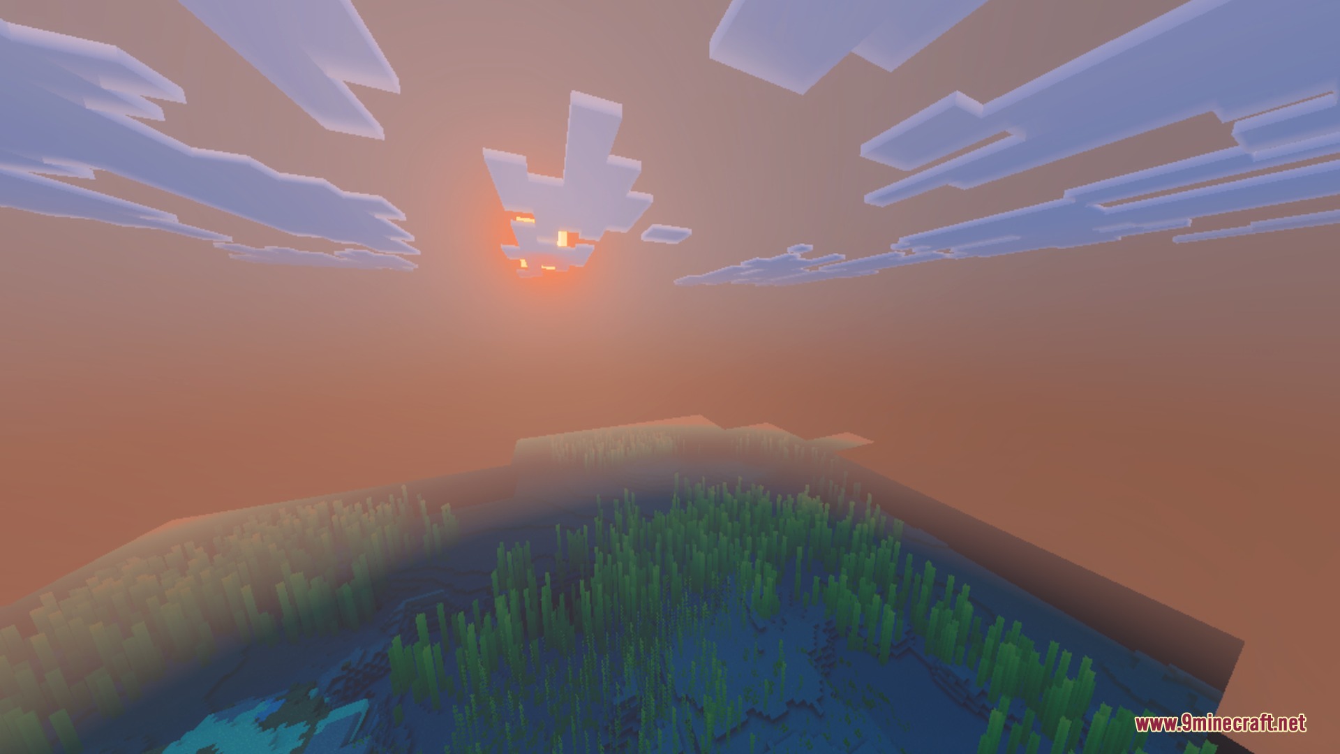 A vibrant sunset over the ocean with kelp visible underwater and clouds