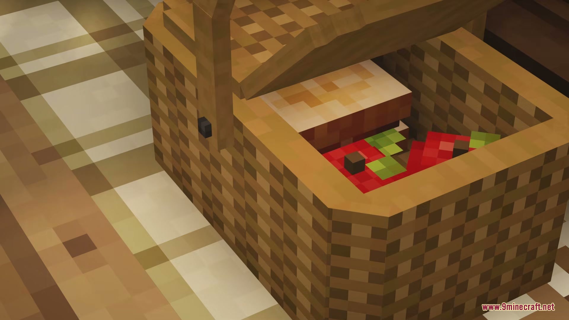 Woven picnic basket containing red apples and a sandwich on a checkered tablecloth