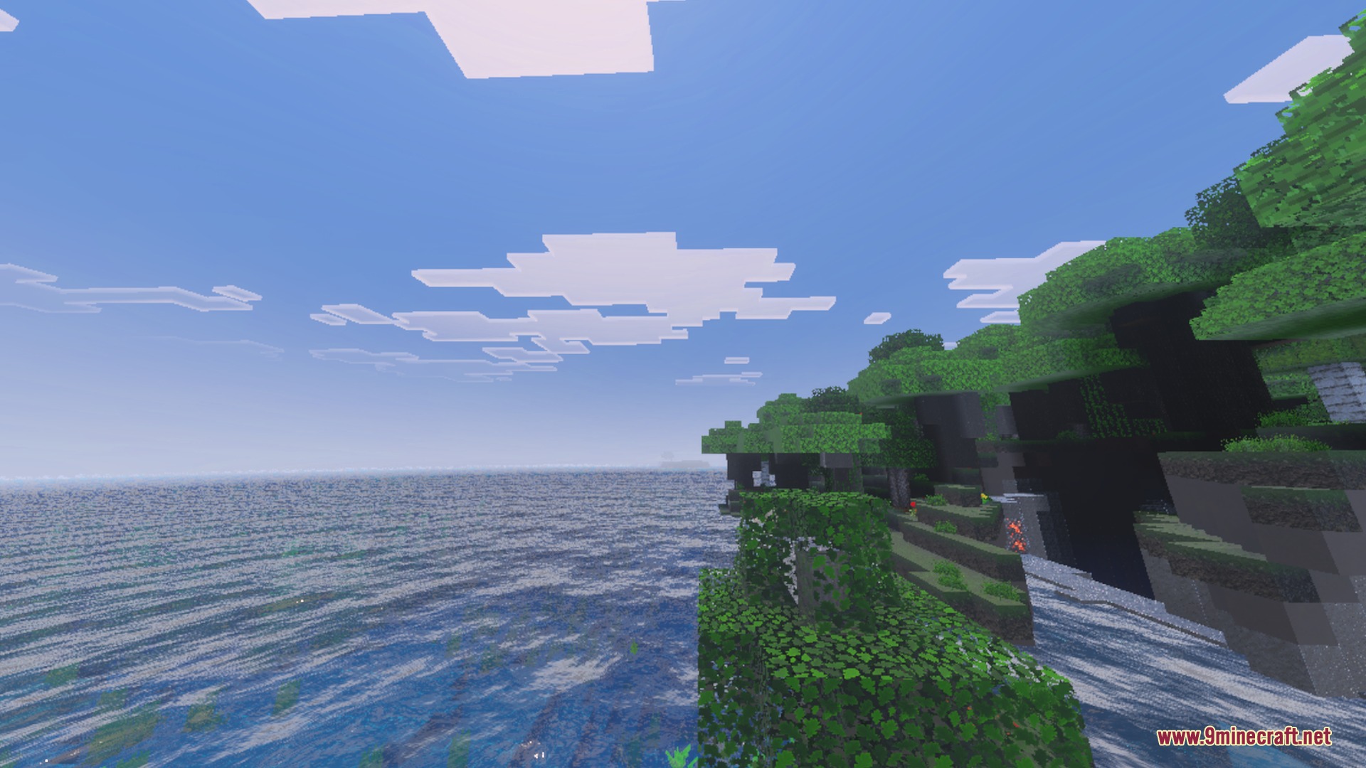 Lush green trees on a rocky cliffside overlook the realistic blue ocean