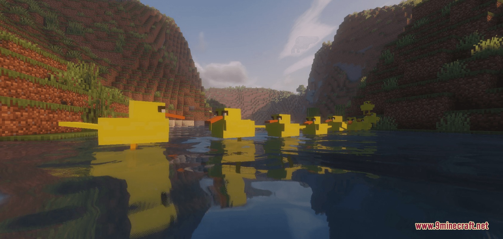 A line of yellow ducks swimming across a river in a mountain valley