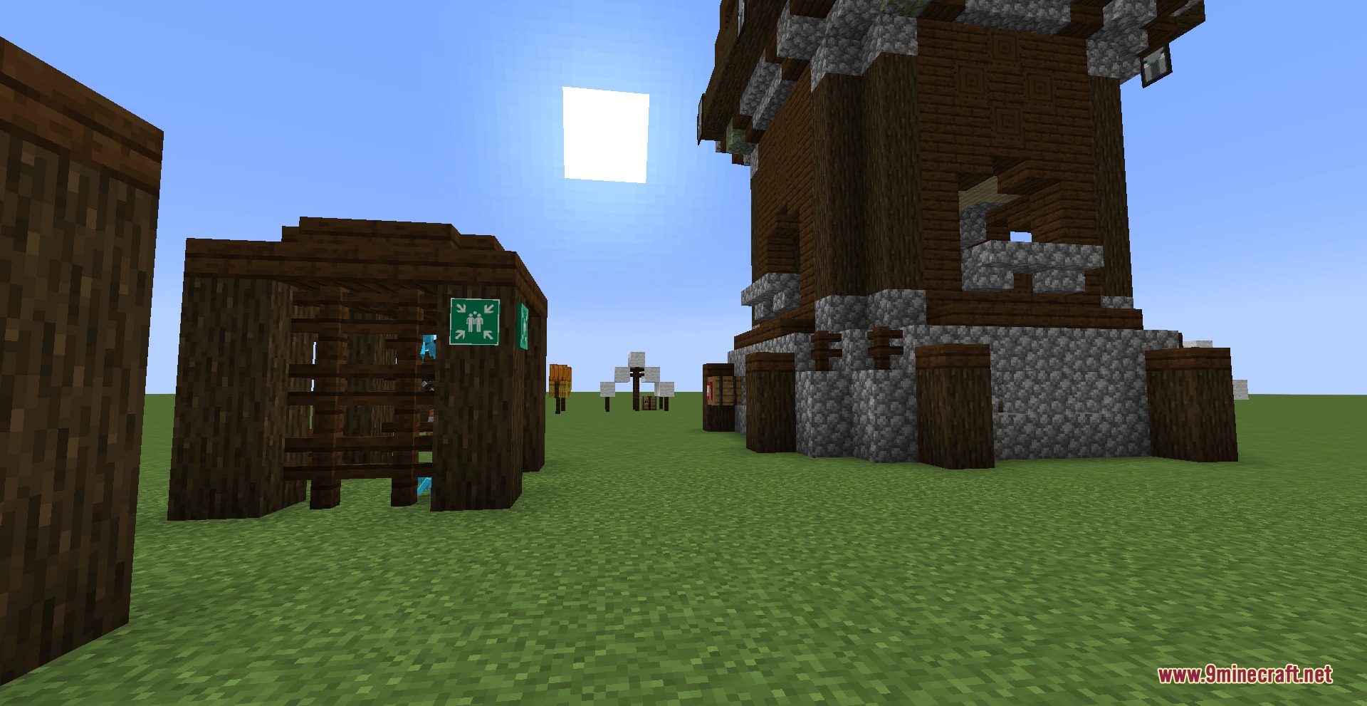 An assembly point sign attached to a wooden building in a grassy field