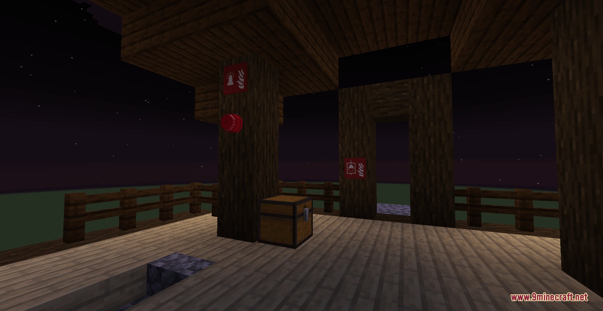 Fire alarm bell and emergency signs mounted on a wooden pillar at night