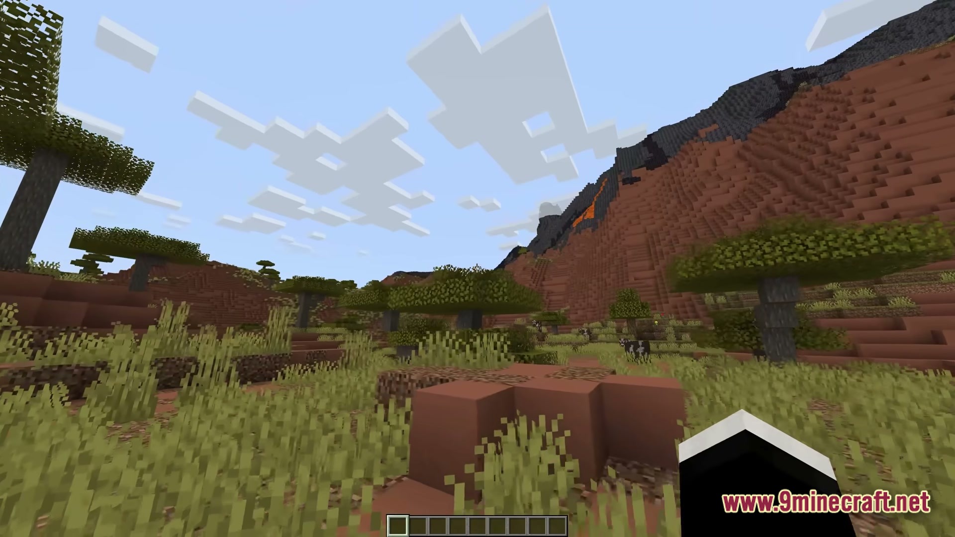 FF's Terra Forge Modpack Screenshot 1 A savanna biome featuring acacia trees, tall grass, and a large red sand mountain with lava