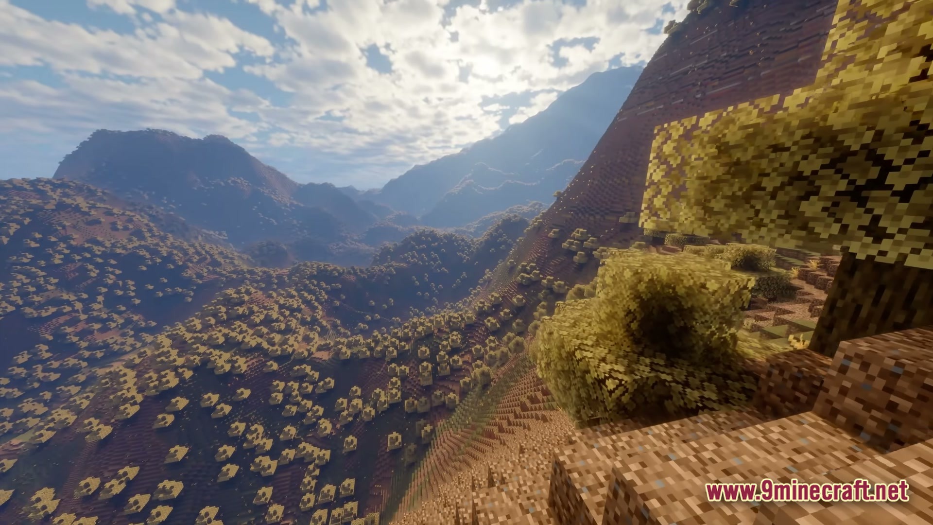 FF's Terra Forge Modpack Screenshot 4 Large mountainous terrain with yellow-leafed trees under a bright sky with realistic clouds