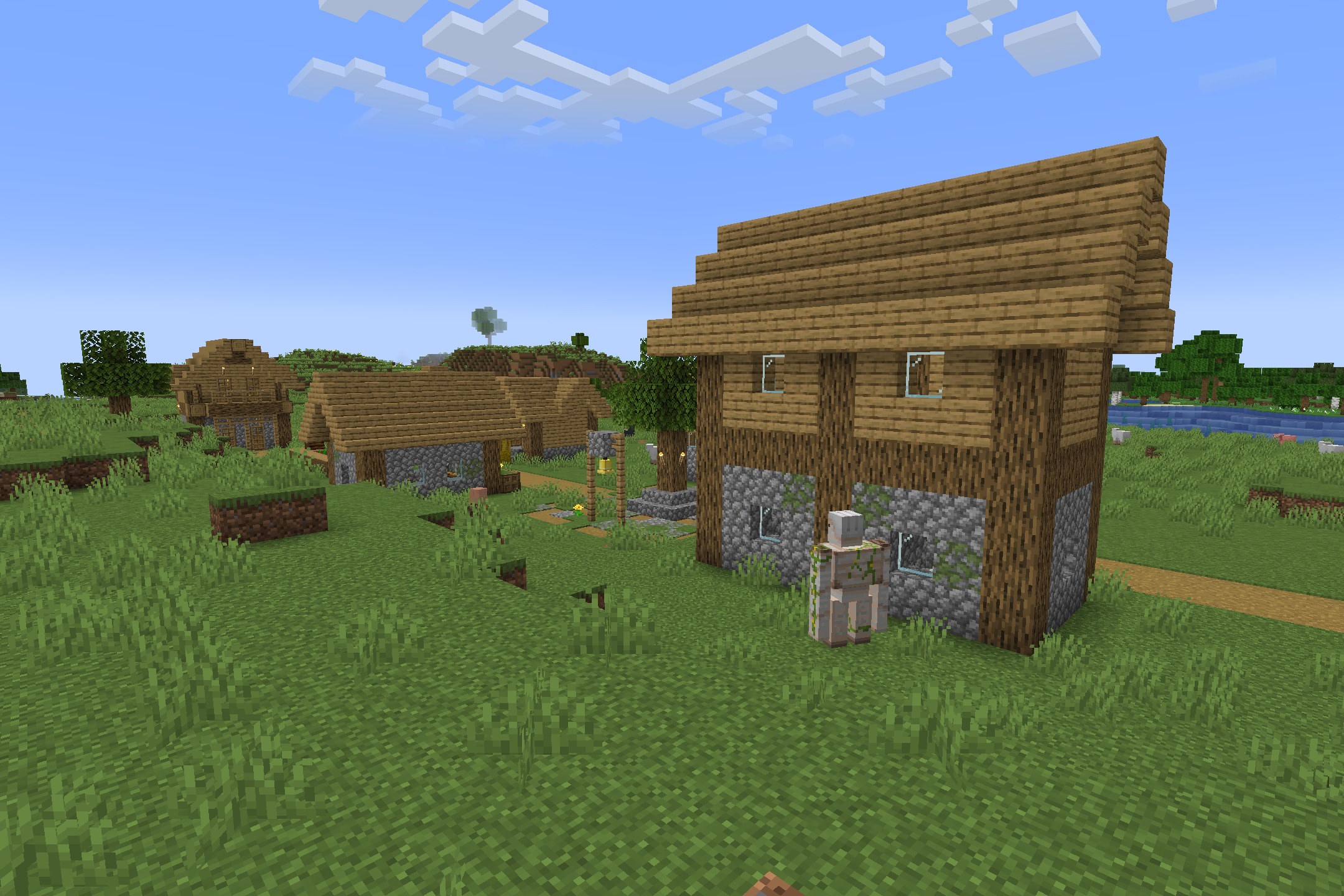 A peaceful Minecraft village with wooden houses and an iron golem standing guard