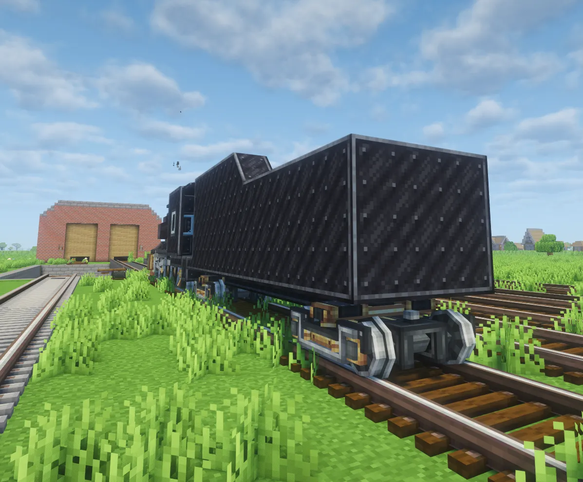 A detailed black steam engine tender on tracks near a brick building