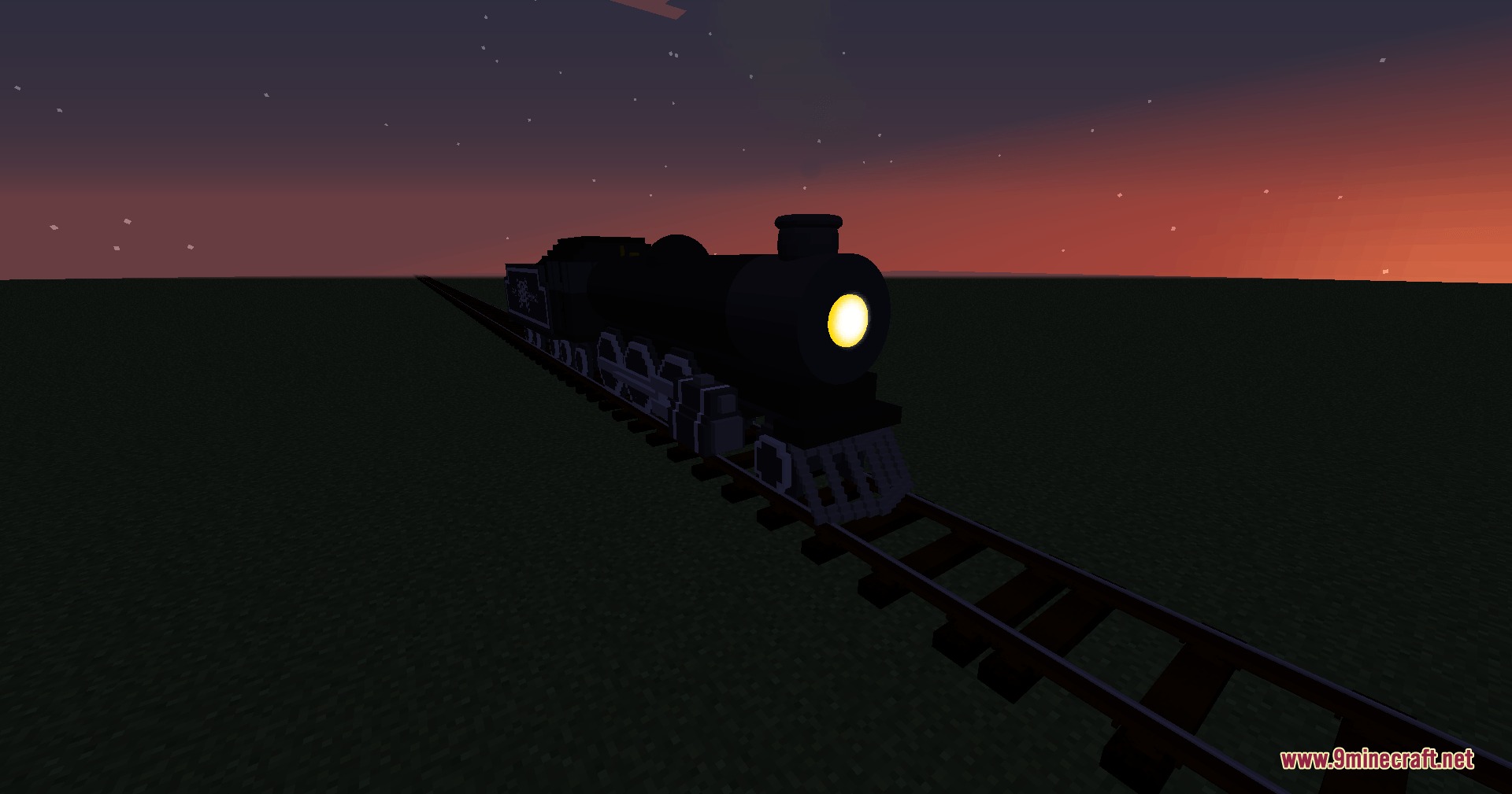 RTLC steam locomotive with a glowing headlight travels on tracks at sunset