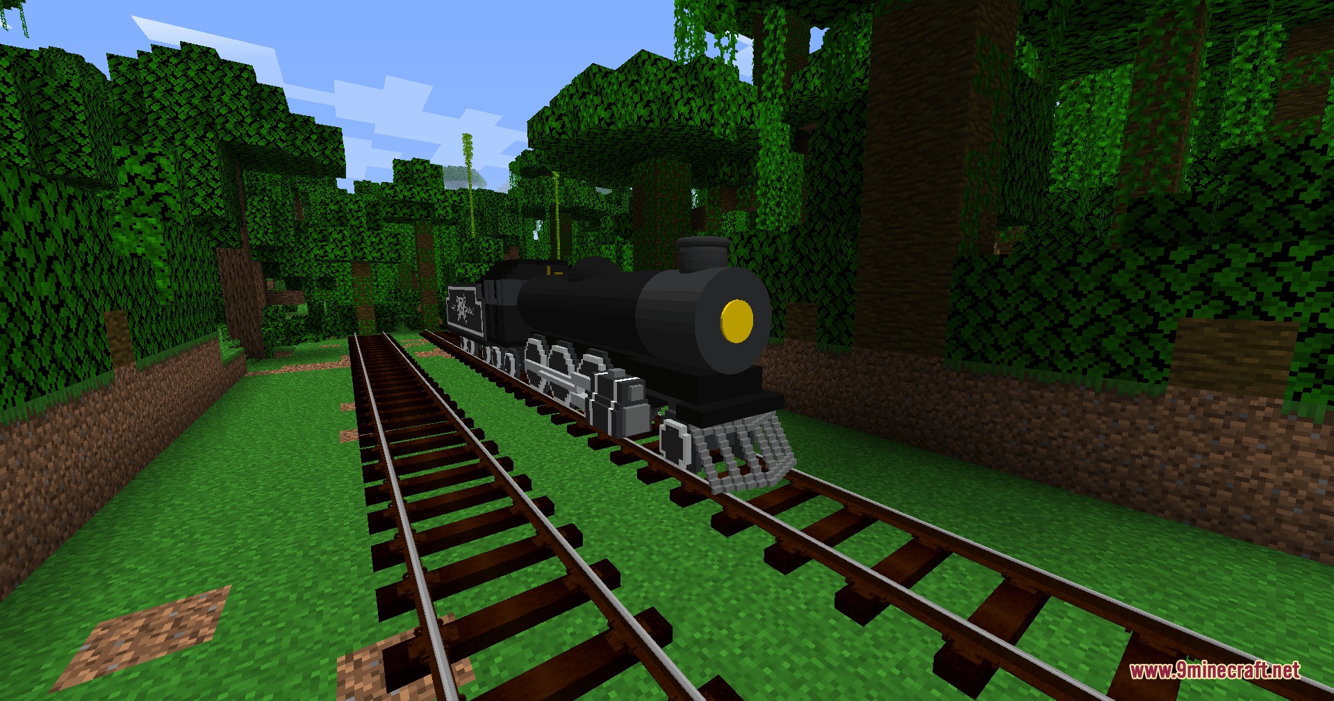 A large black steam locomotive traveling on tracks through a dense jungle