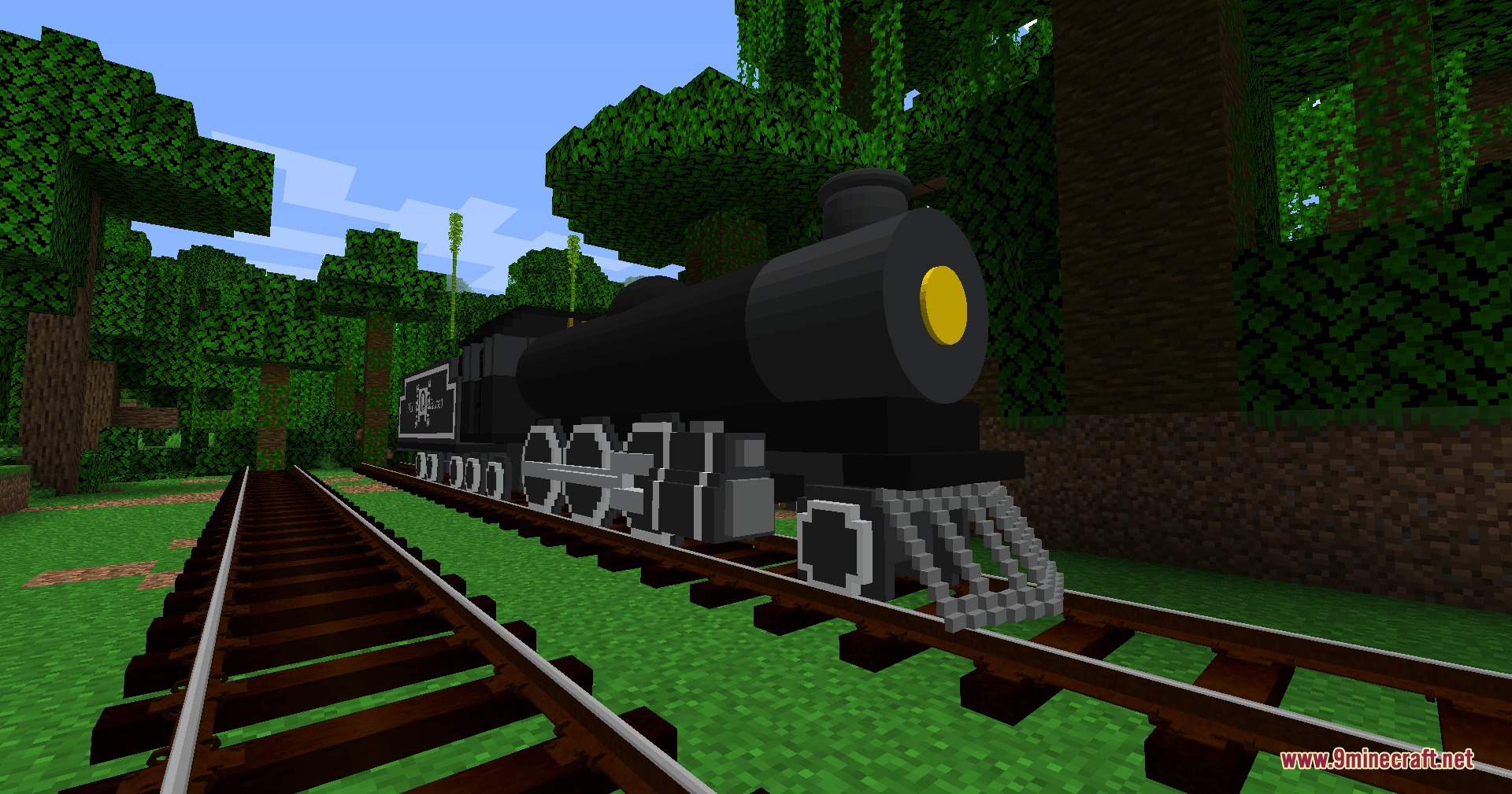 A black steam locomotive with a yellow headlight on a jungle track