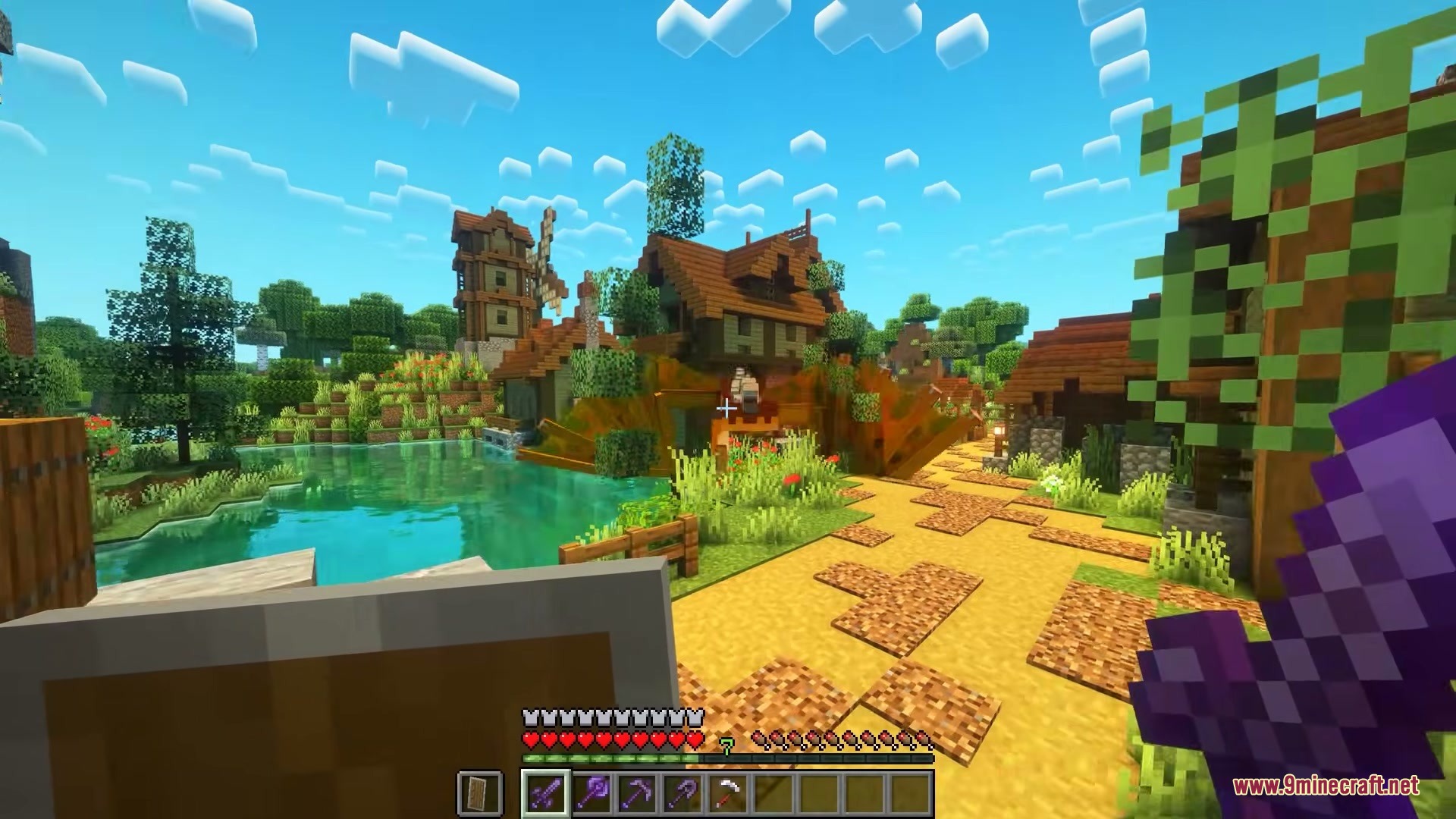 Player stands near a pond and wooden houses in a bright Minecraft village