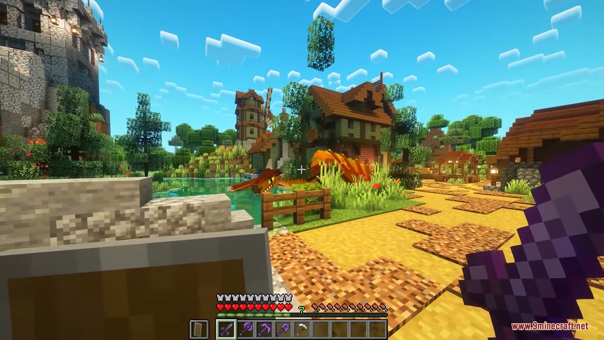 A player holding a netherite sword stands near a dragon in a village