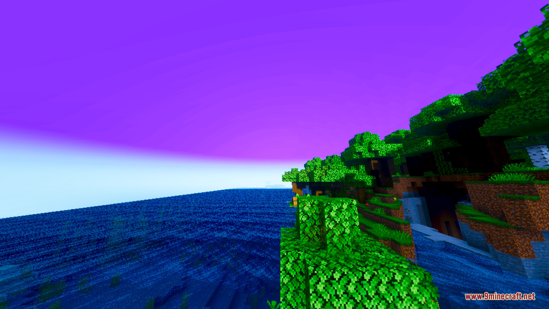 Atmospheric purple sky and deep blue ocean next to a lush green cliffside