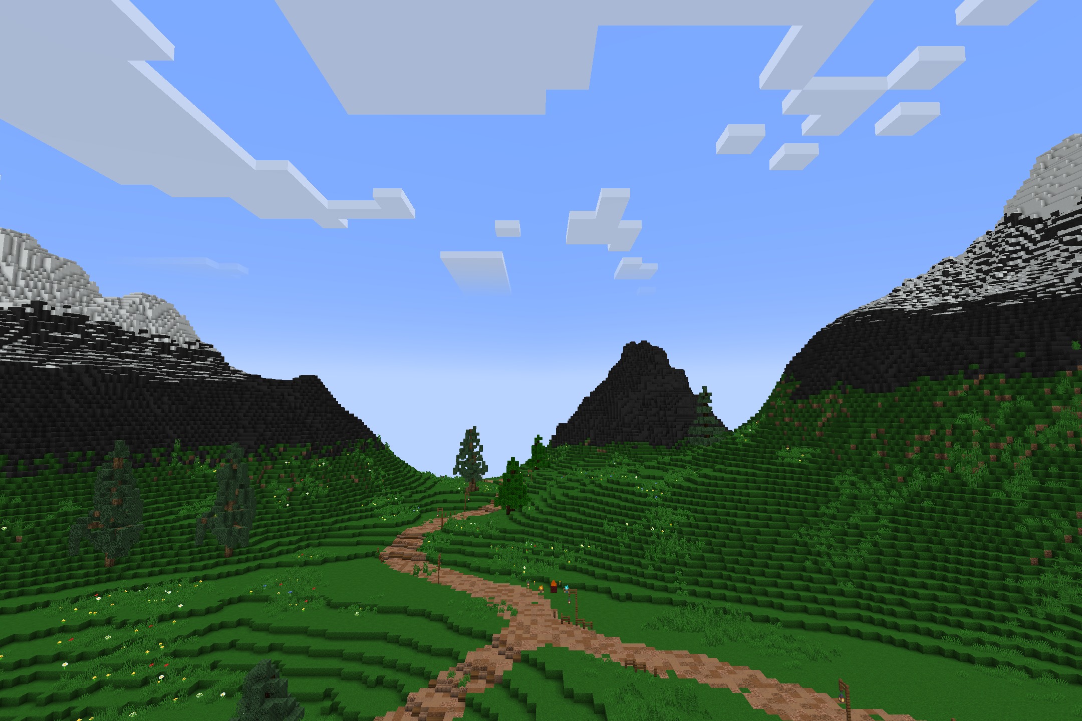 Winding dirt path leading through a lush green valley toward dark mountains