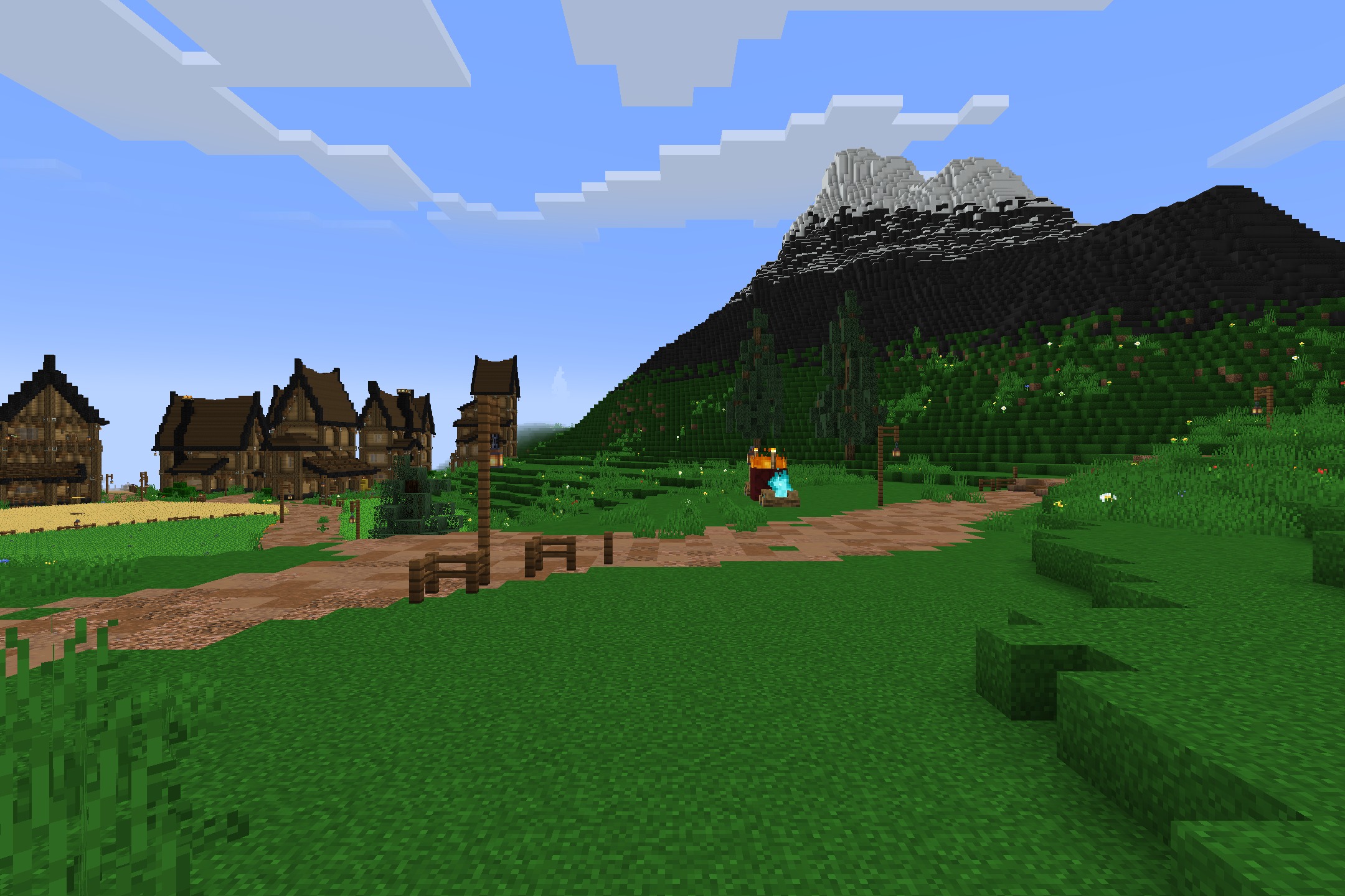 Village buildings and a dirt path set against a tall snowy mountain