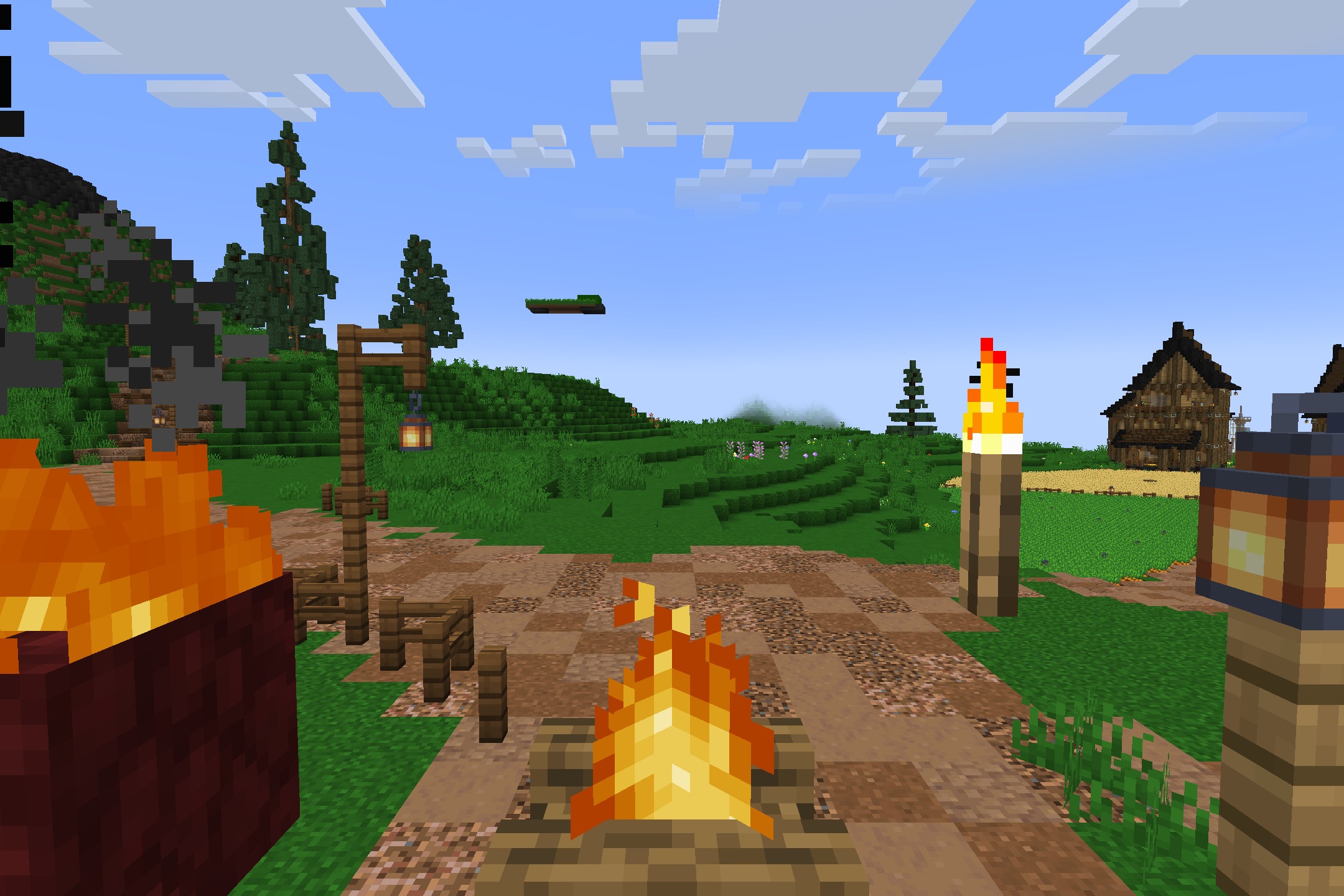 Campfires and torches light up a grassy path near a small village