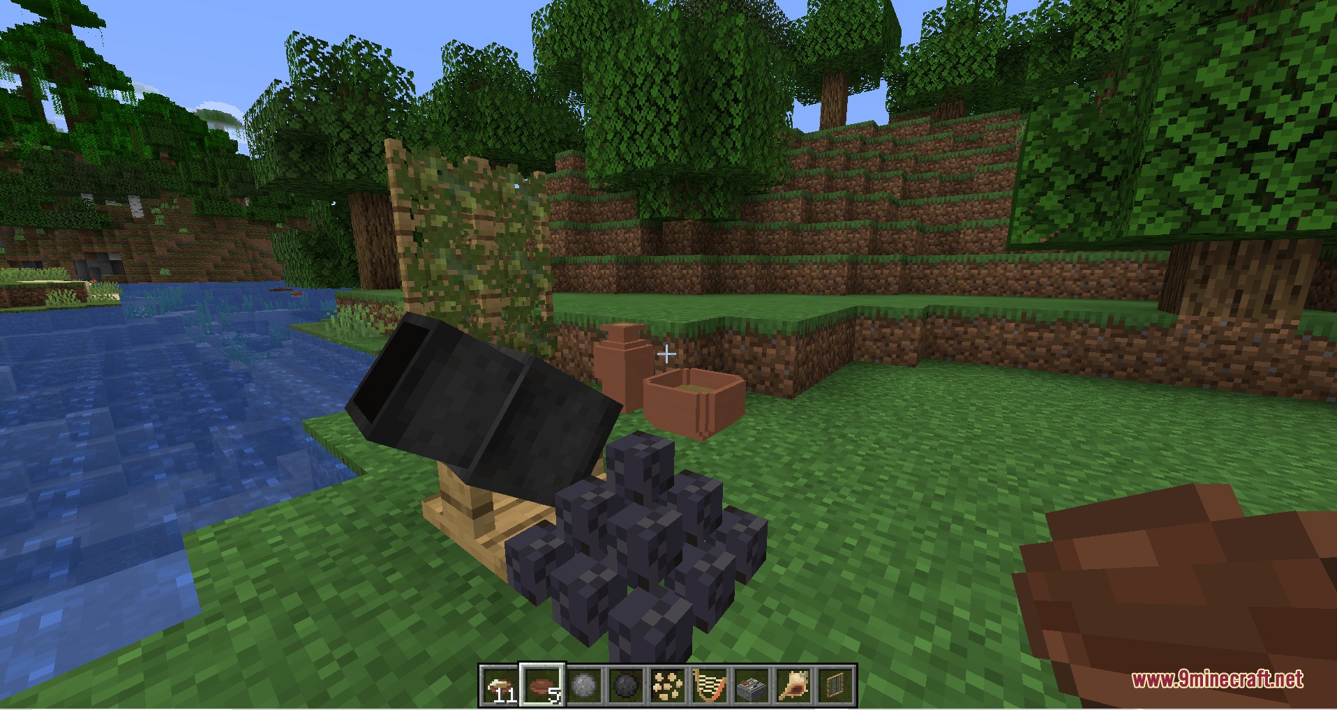 A black cannon and a pile of cannonballs placed on the grass