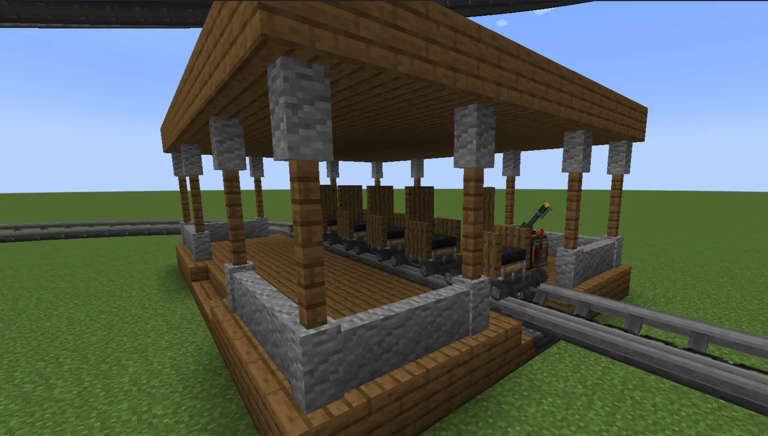 Six linked carts sitting inside a wooden station on a rollercoaster track