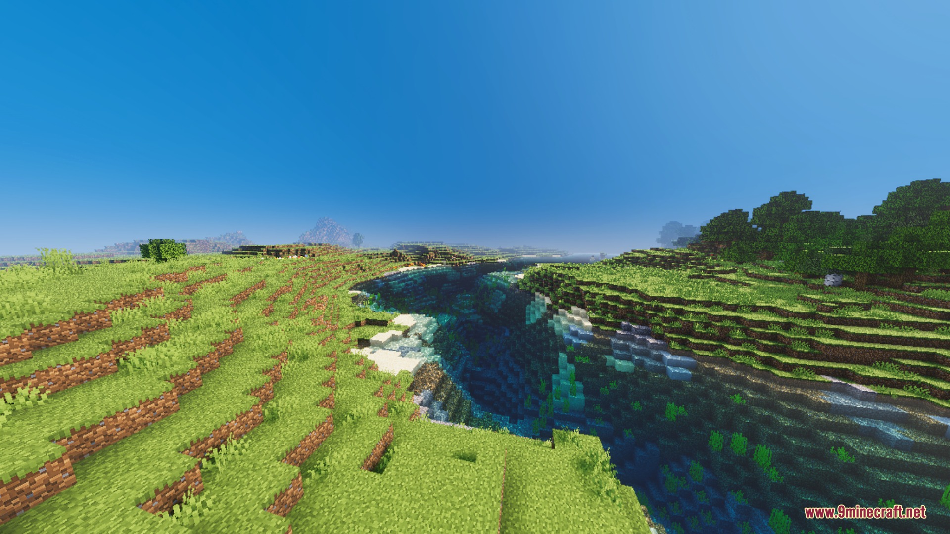Lush green landscape with a deep river under a clear blue sky