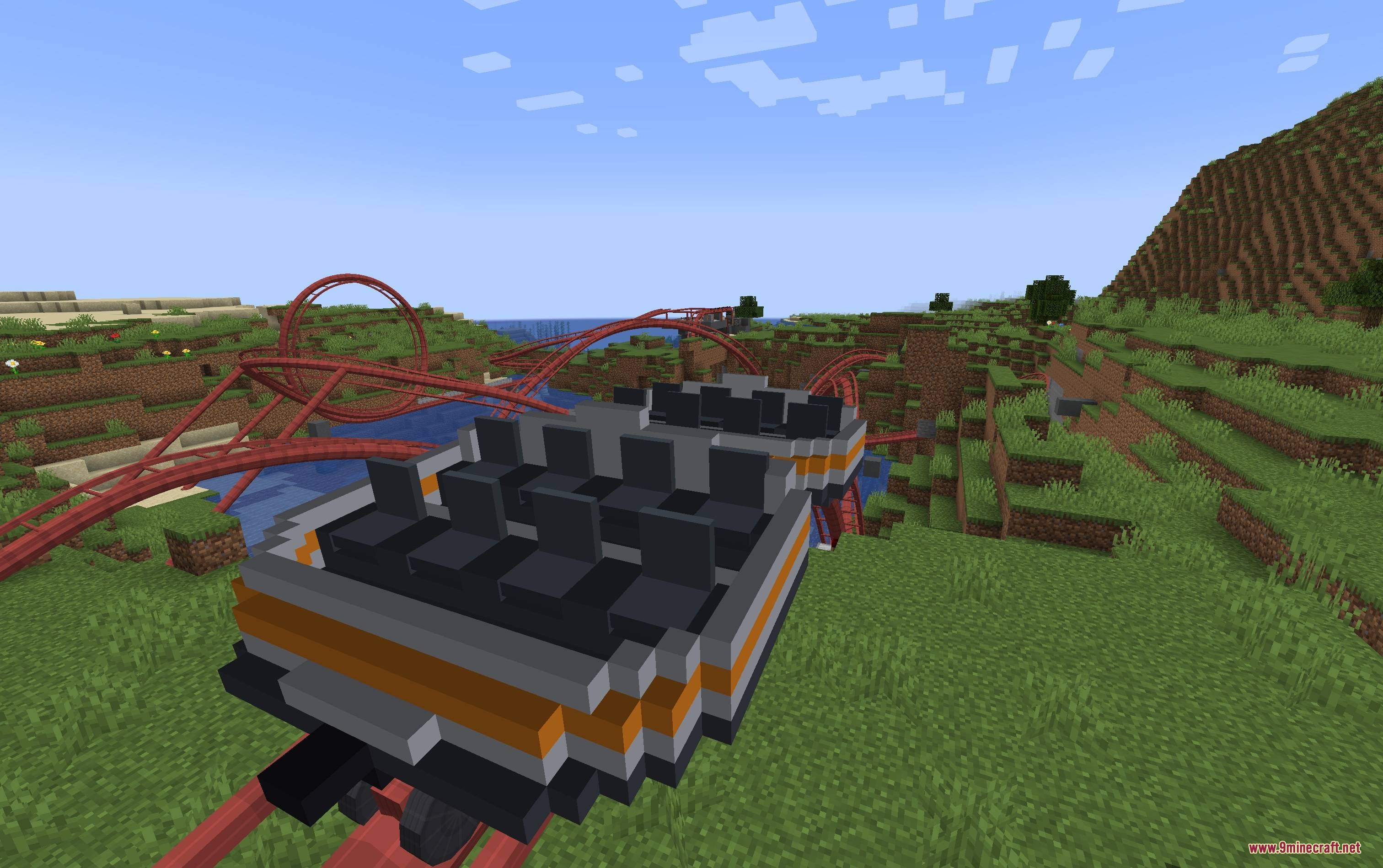 Mine Coasters Mod Screenshot 6 A custom roller coaster train traveling on red tracks through a grassy landscape