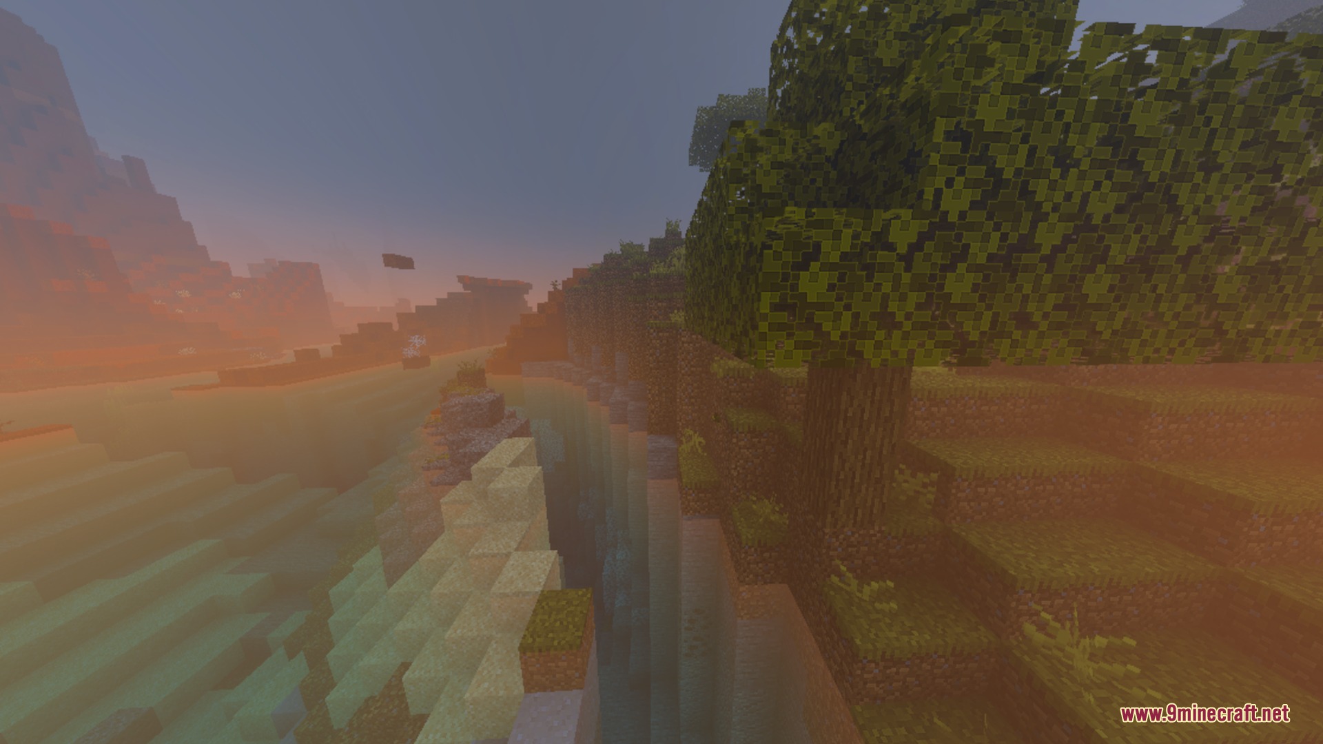 Soft orange sunset fog covers a river valley and green hills