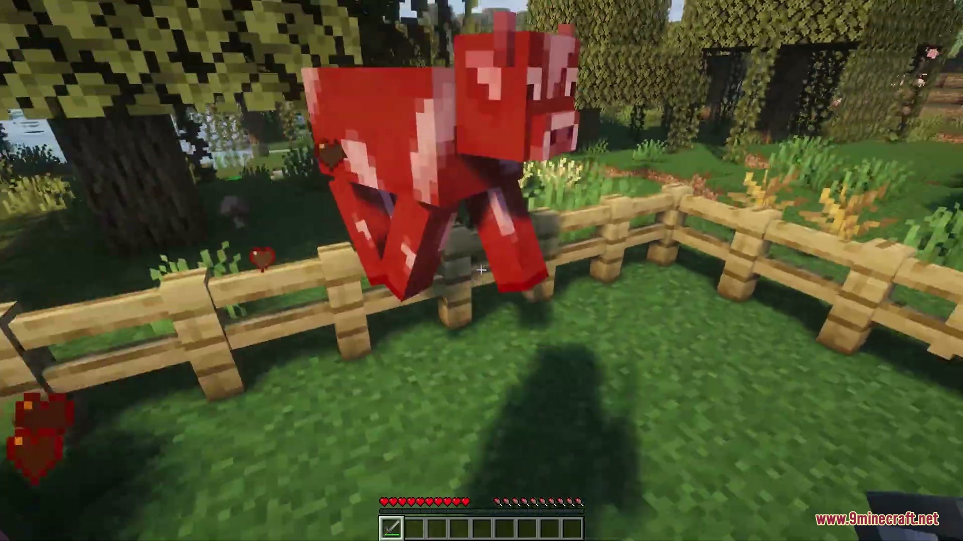 Name Tag Upgrade Mod Screenshot 4 A red cow jumps over a wooden fence with heart particles nearby