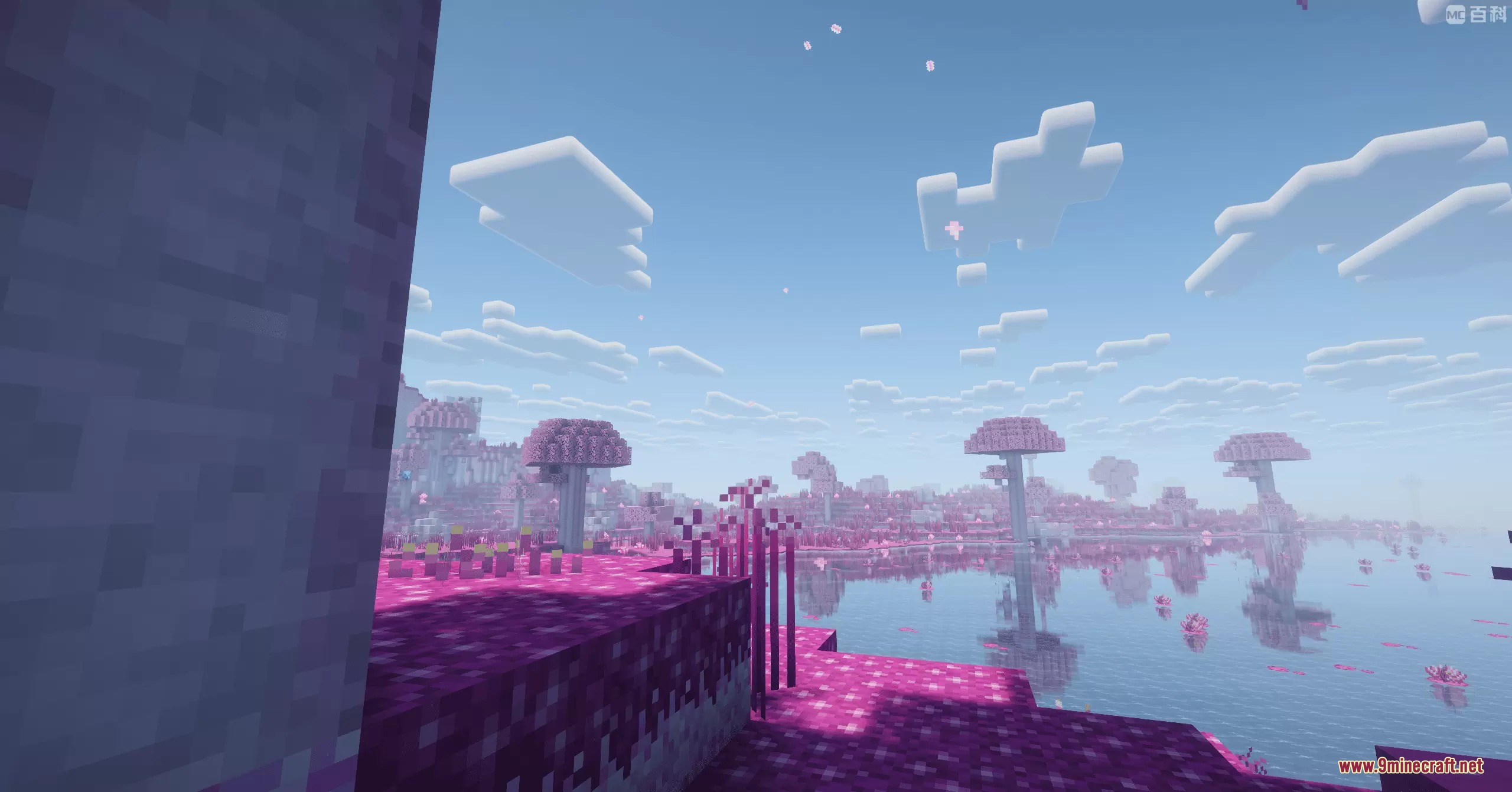 Pink mushroom trees and vibrant grass surround a calm lake under a clear sky