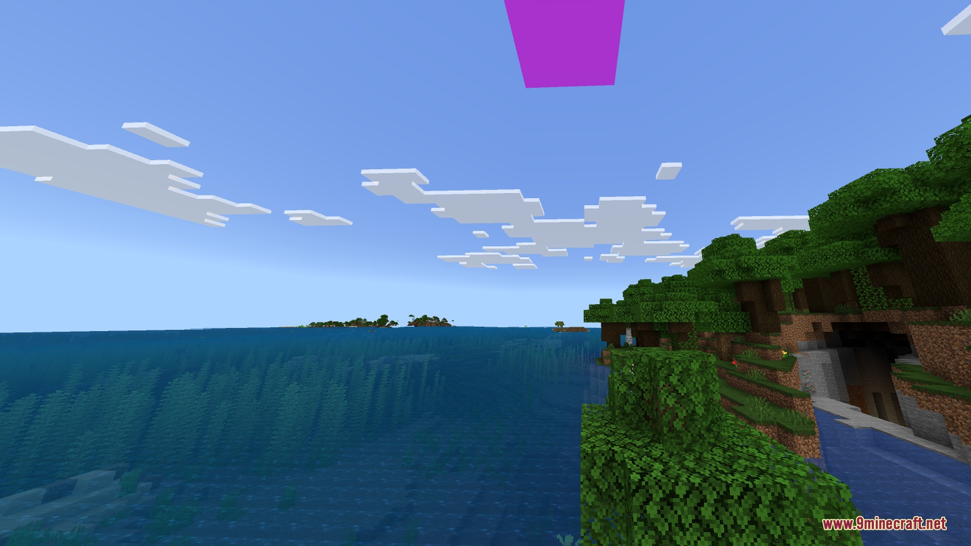 Lush green forest cliff overlooking a vast ocean with white blocky clouds above