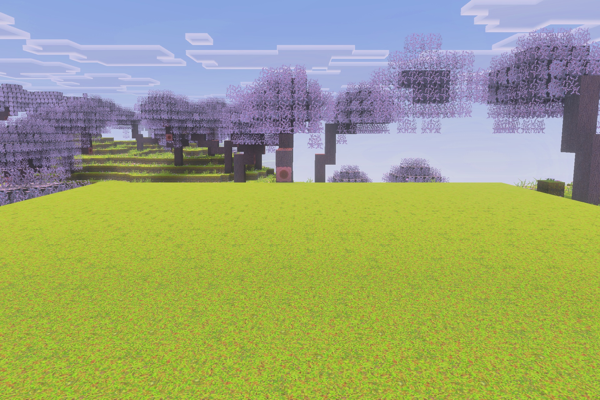 A scenic view of cherry blossom trees and a vast green field