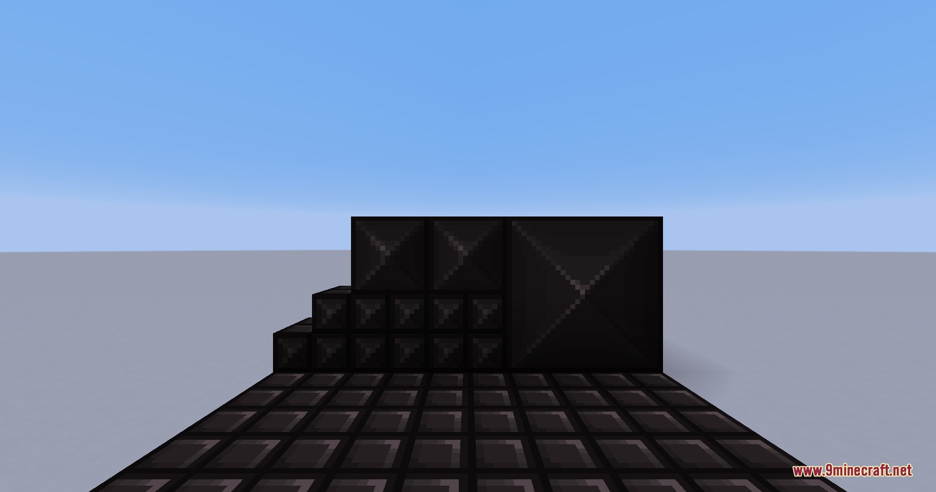 Dark metallic blackplate blocks arranged in a simple structure on flat ground