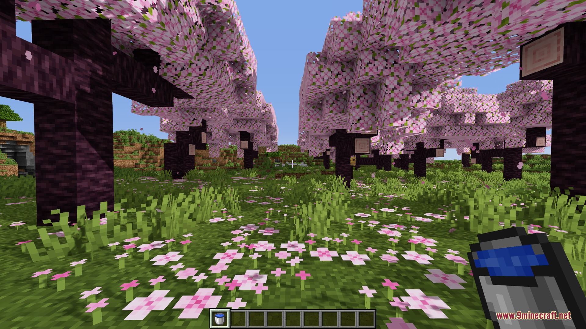 PvP Smaller Hand Helds Resource Pack Screenshot 2 Player holding a small water bucket while standing in a cherry grove