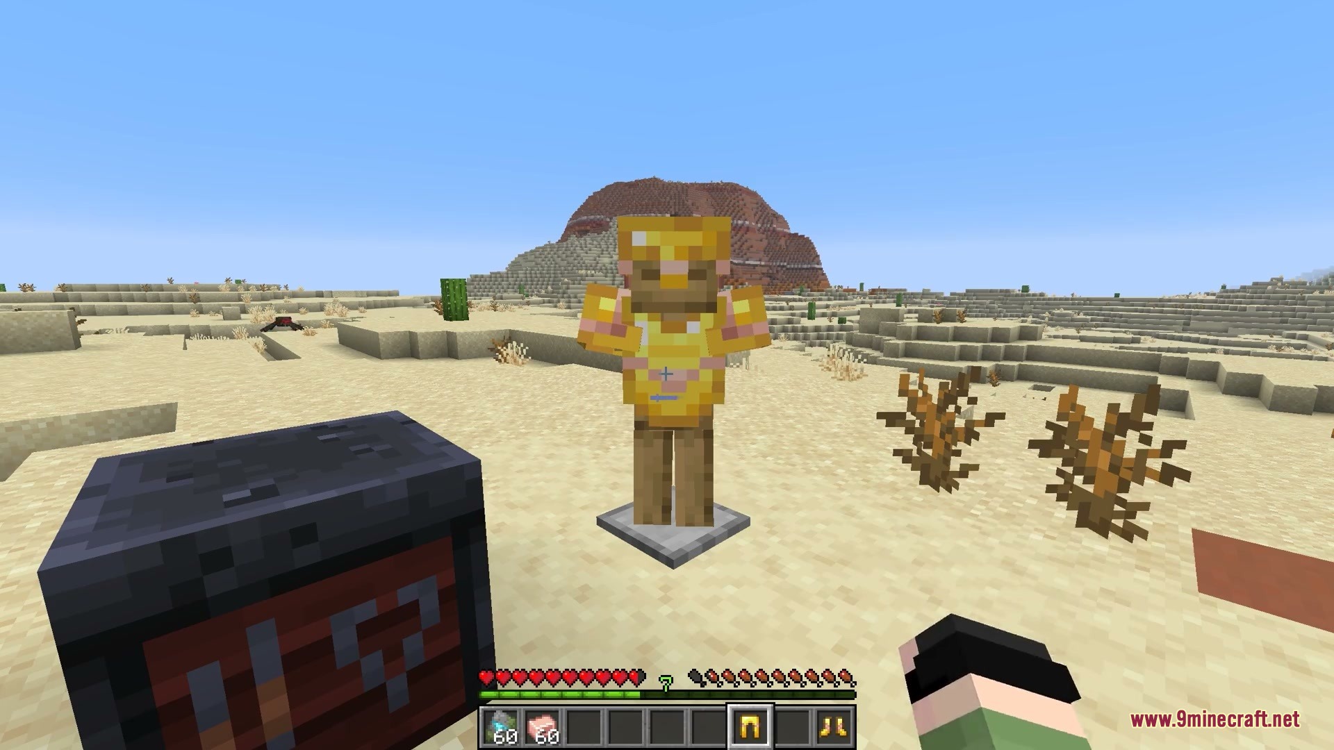 Golden armor with glowing trims displayed on an armor stand in the desert