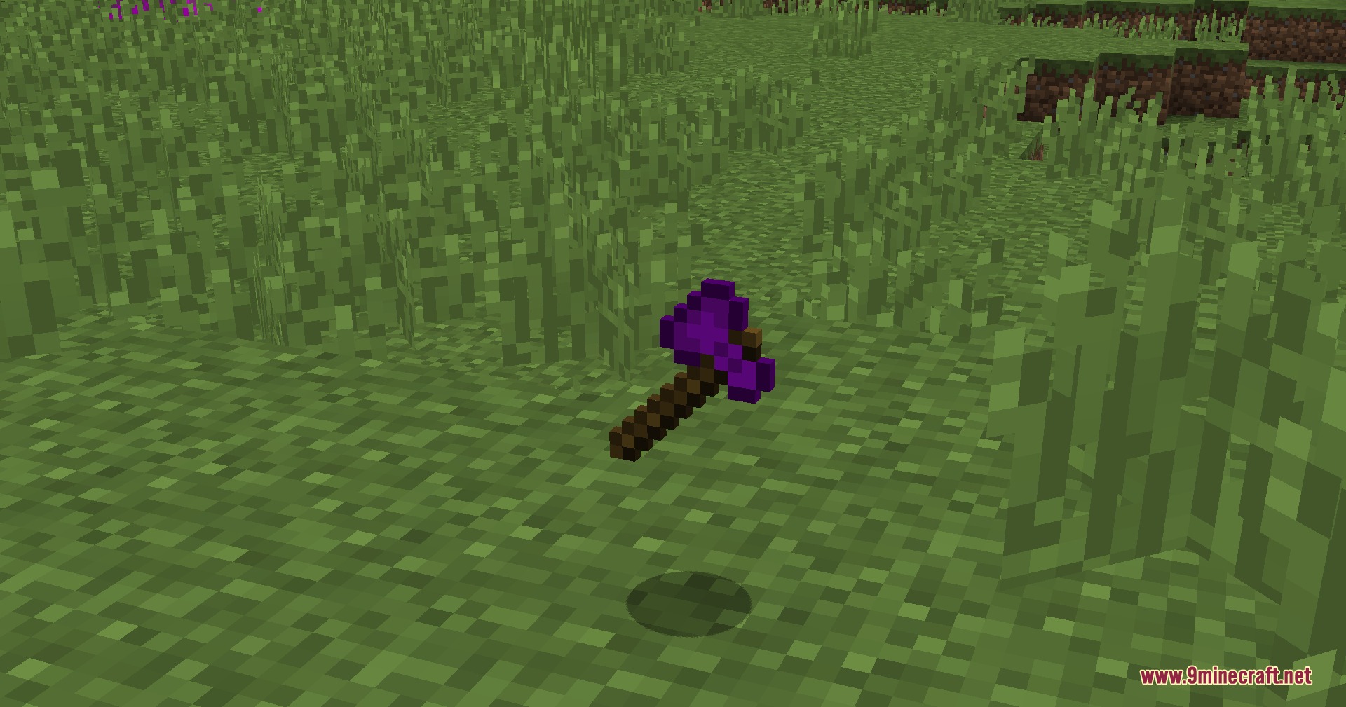 A purple axe tool dropped on the grass in a Minecraft world