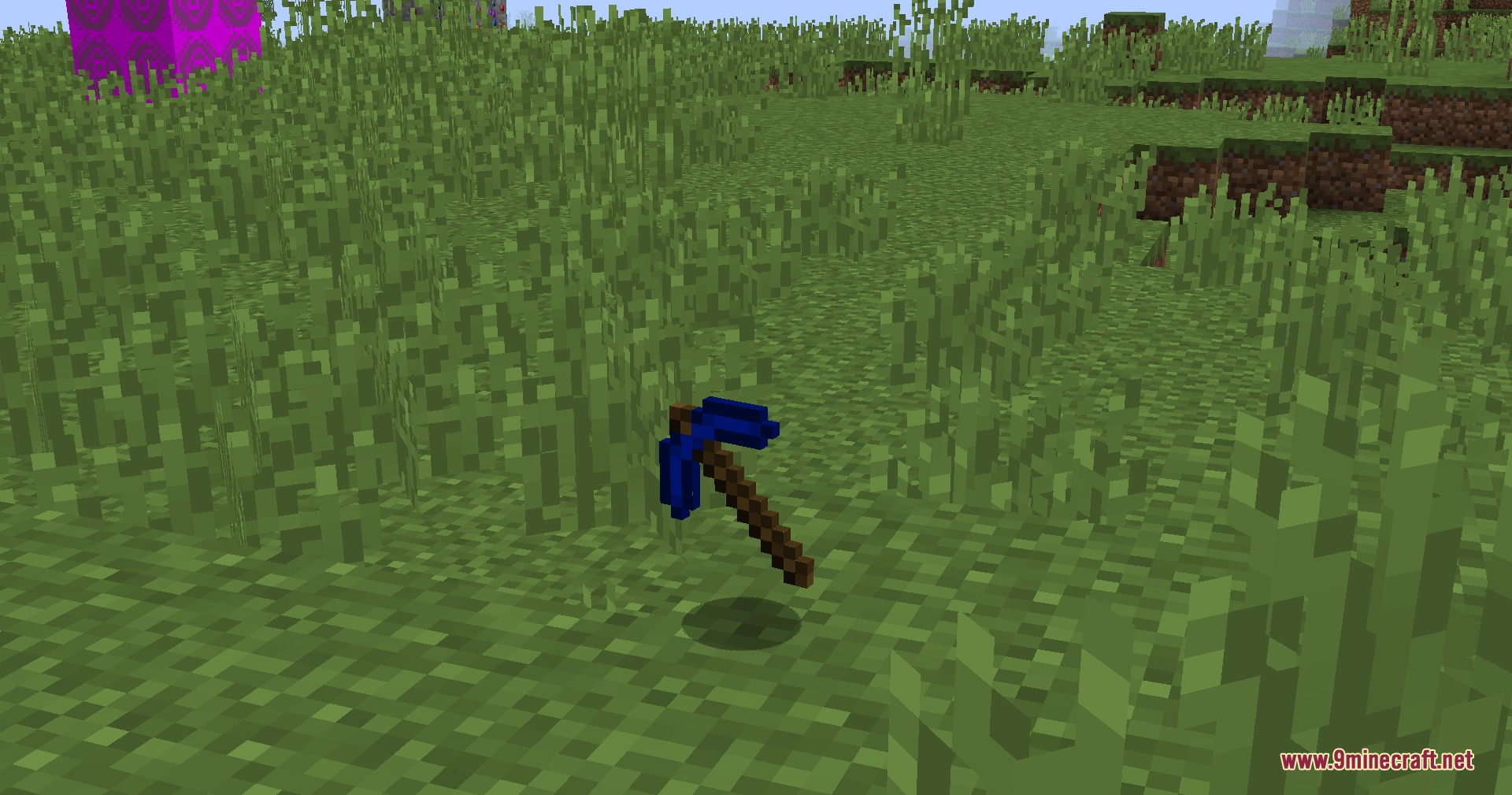 A blue pickaxe made from new materials floats above the green grass