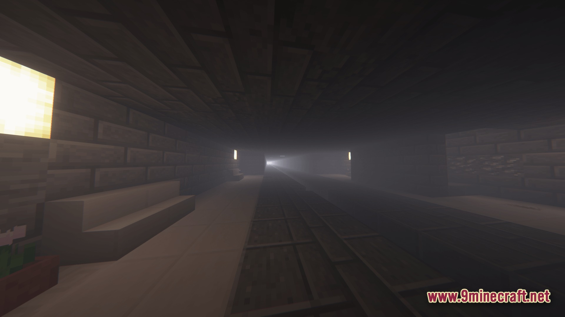 A dark, foggy underground subway station with stone brick walls and a long train track