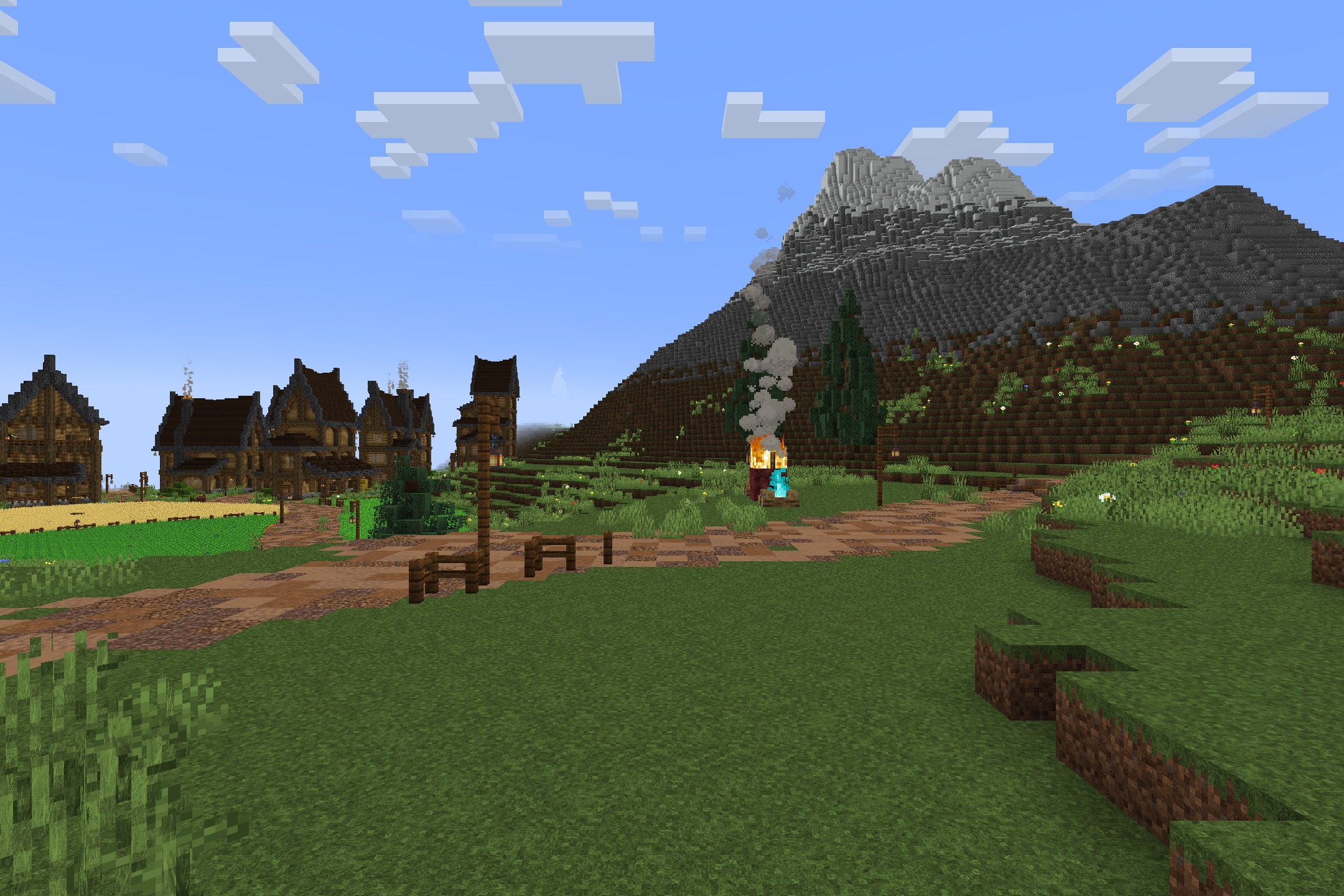 Realtastic X512 PBR POM Resource Pack Screenshot 2 Village houses and a soul campfire near a tall rocky mountain under blue sky