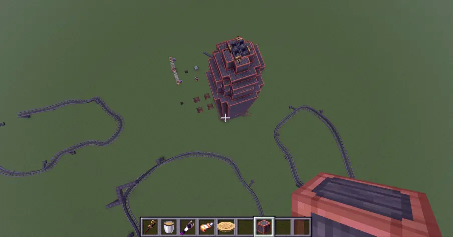 Top down view of a rocket ship surrounded by curved rail tracks on grass