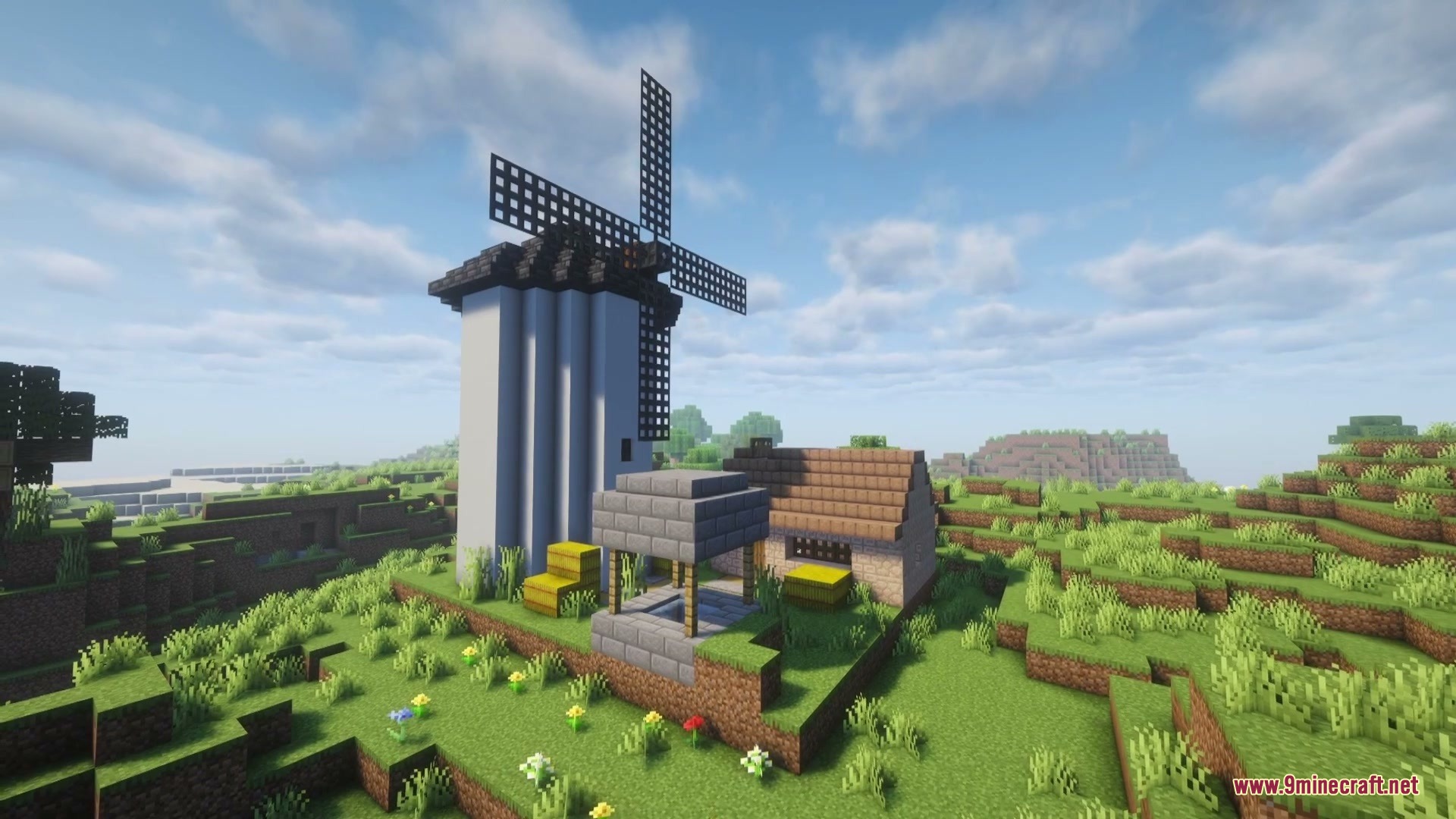 A white windmill and a small stone house stand on a hill