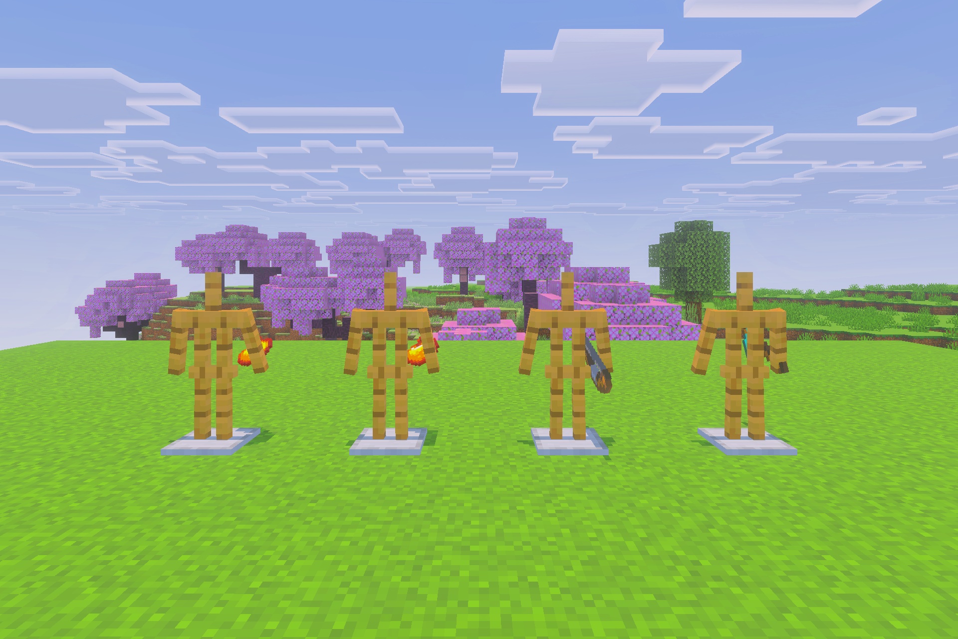 Four armor stands holding items on a vibrant green grass field