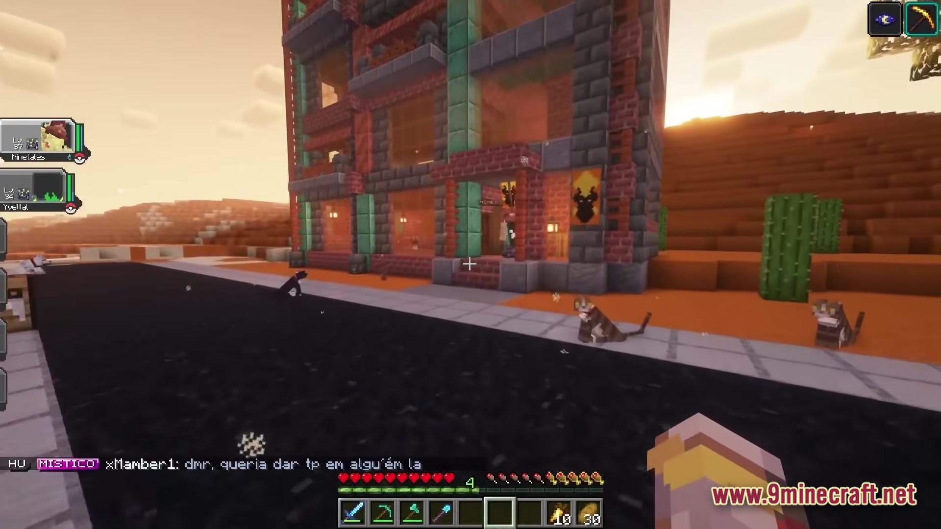 Servidor Jornadas Cobblemon Modpack Screenshot 5 A multi-story brick building stands next to an asphalt road in a desert biome with several cats