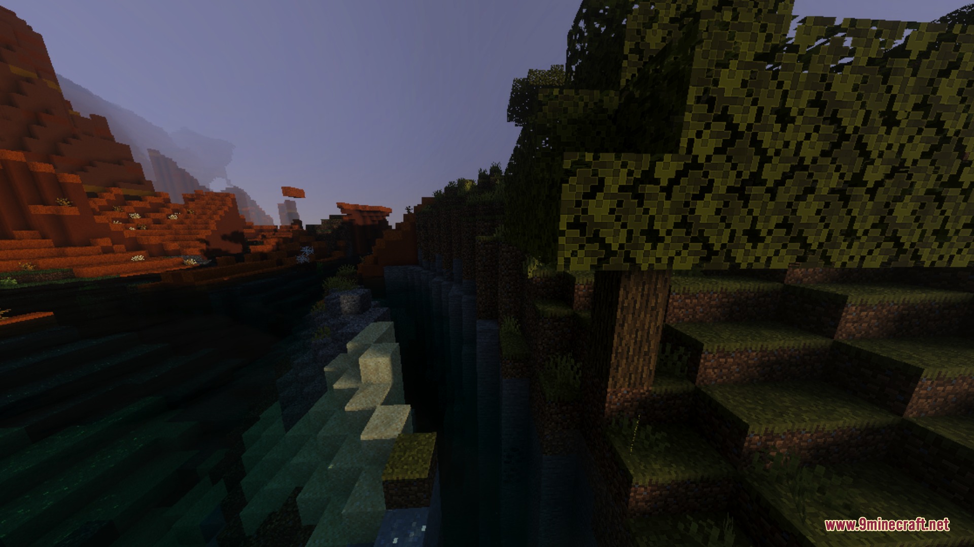 A scenic river valley between a dark forest and red mesa mountains
