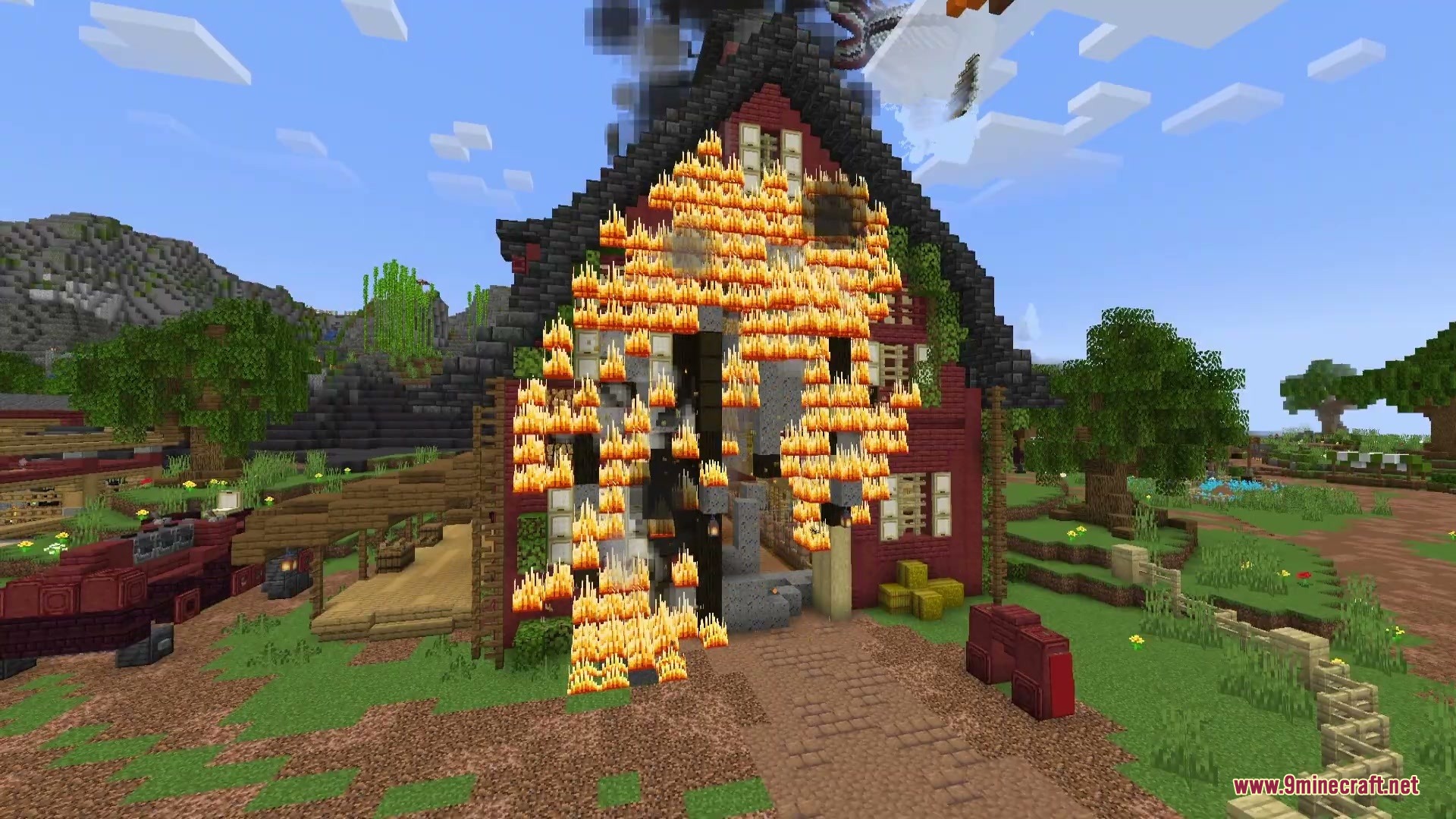 A red wooden barn is engulfed by spreading flames and thick smoke