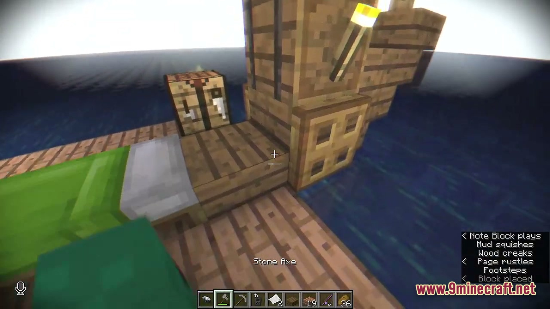 A small wooden raft floating on the ocean with a bed, crafting table, and torch