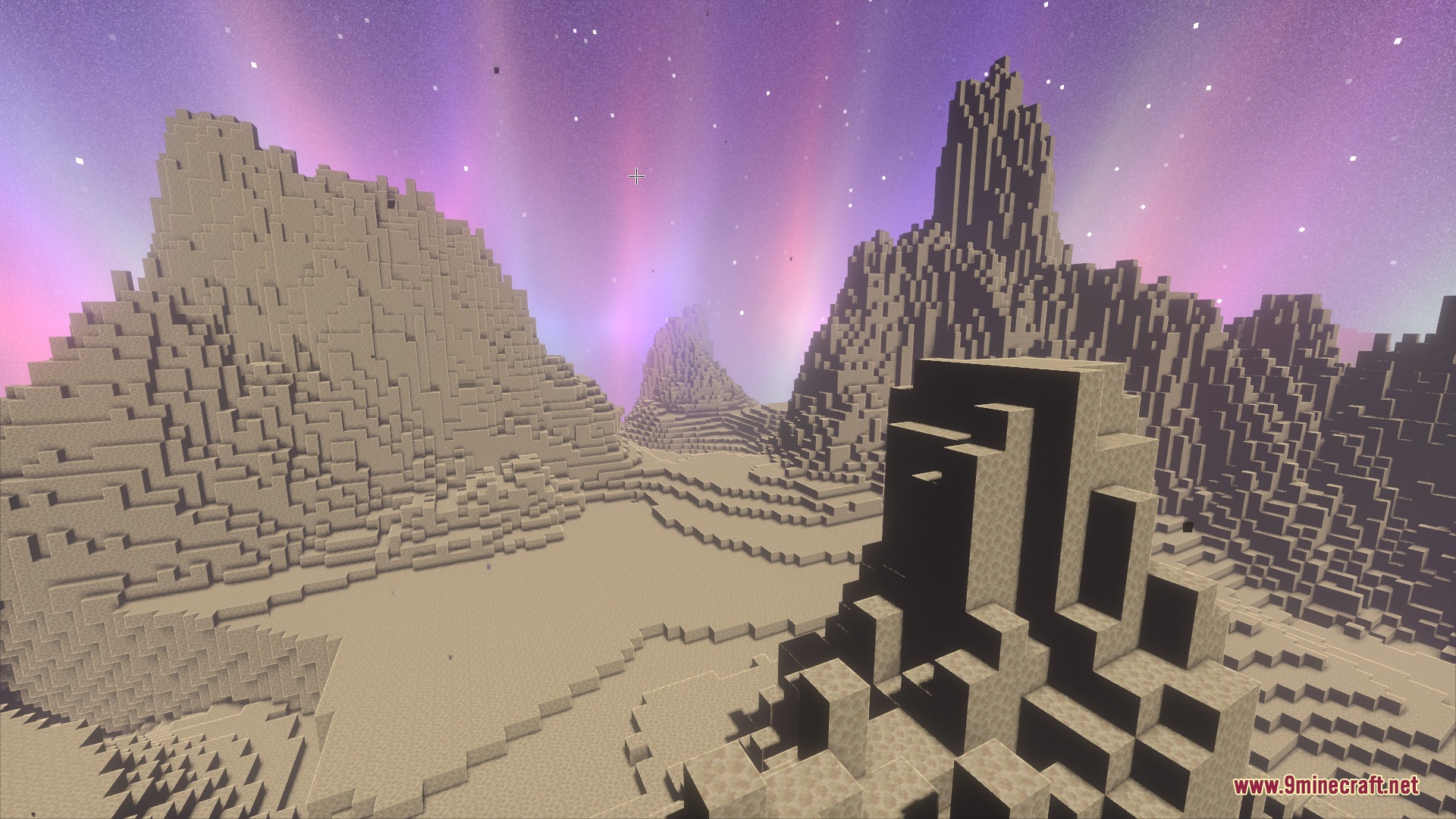 Massive beige mountains stretch across the horizon under a vibrant purple aurora sky