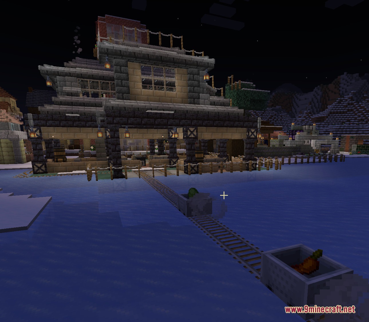Trade Post for Mine Colonies Mod Screenshot 1 A large trade building at night with minecart tracks over frozen water